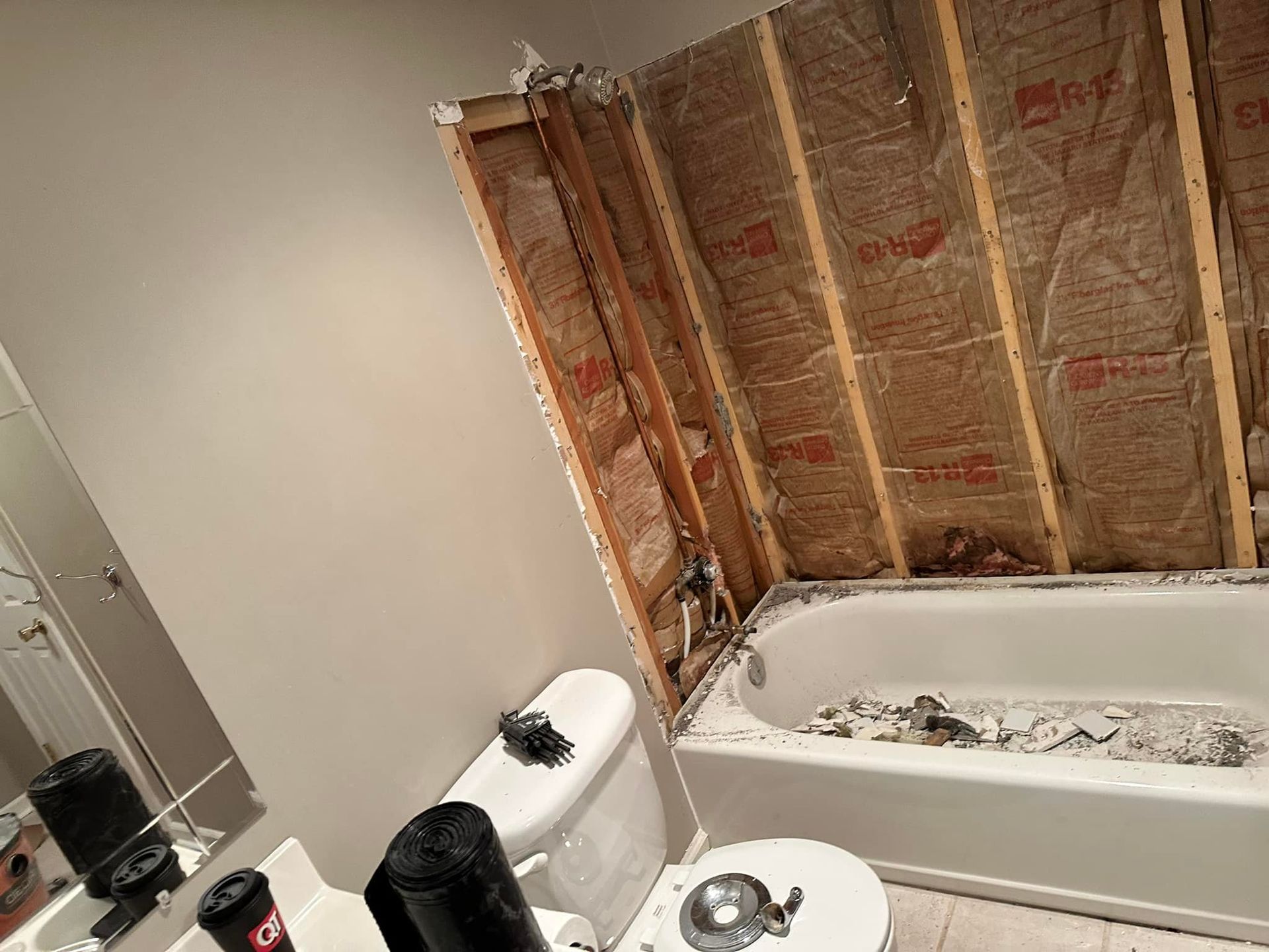 A bathroom with a toilet , tub , and mirror.