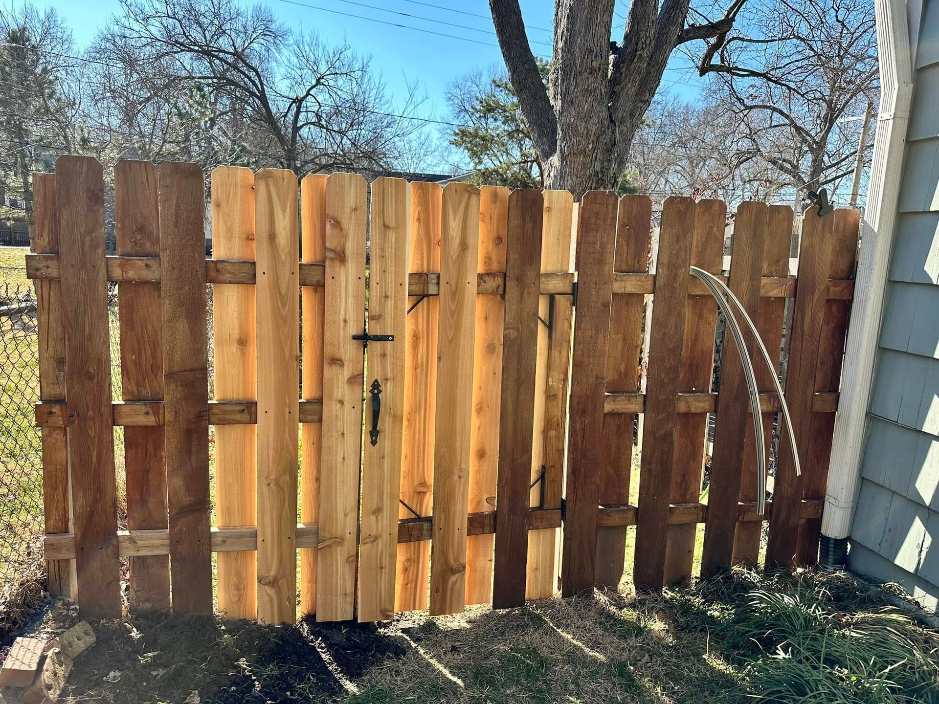A wooden fence with a gate in the backyard of a house.
