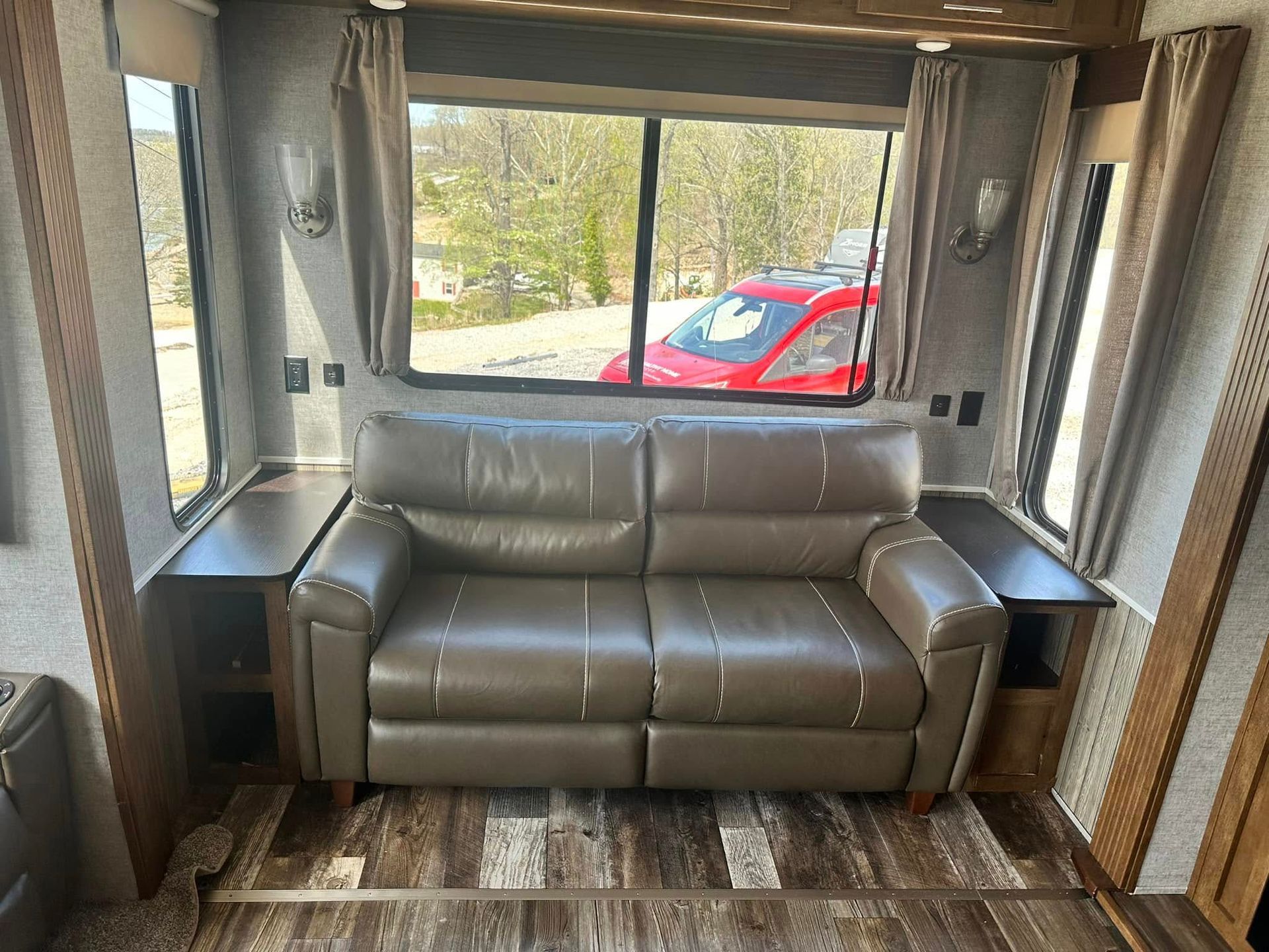 A living room in a rv with a couch and a window.