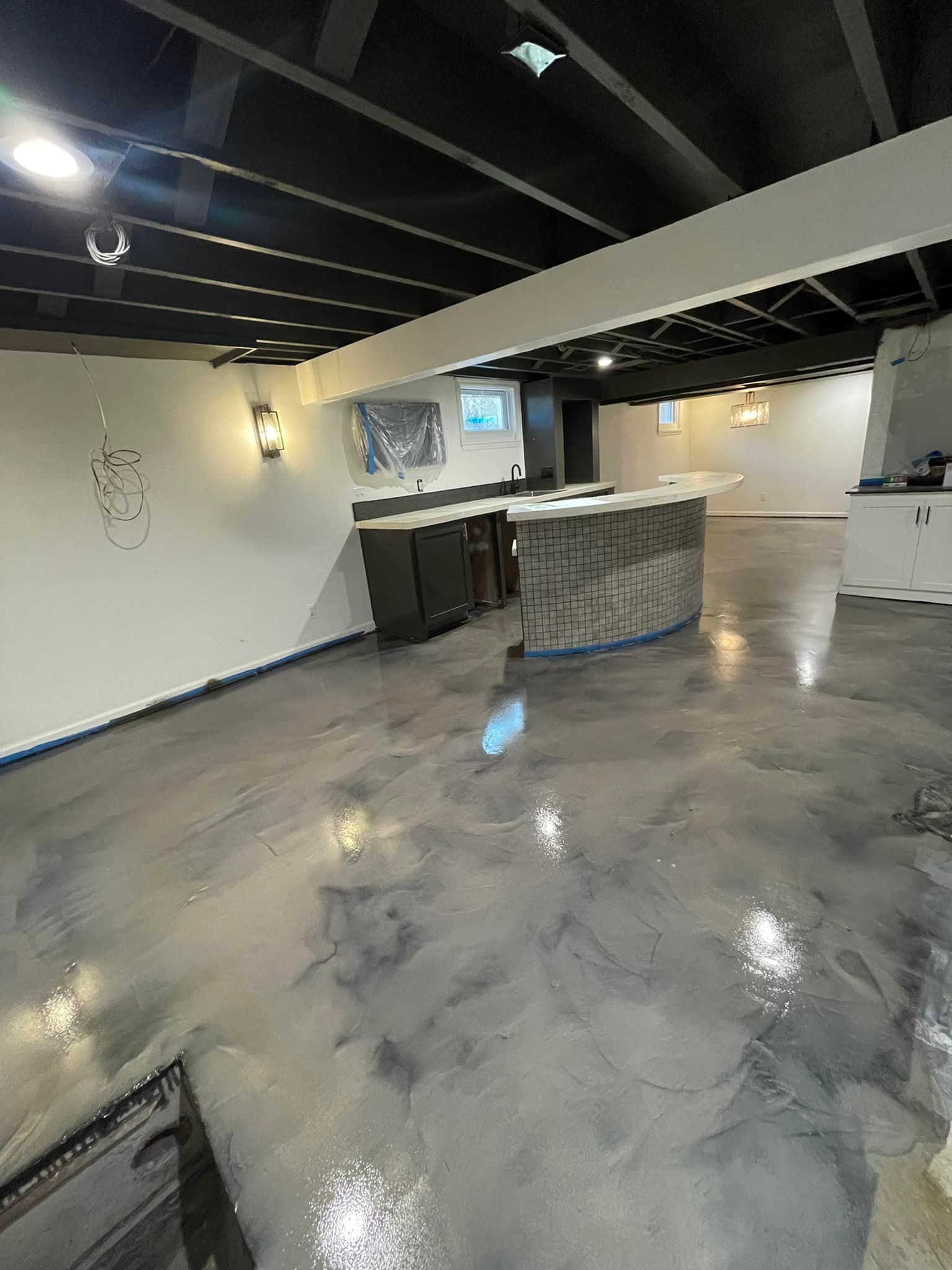 A basement with a concrete floor and a bar.