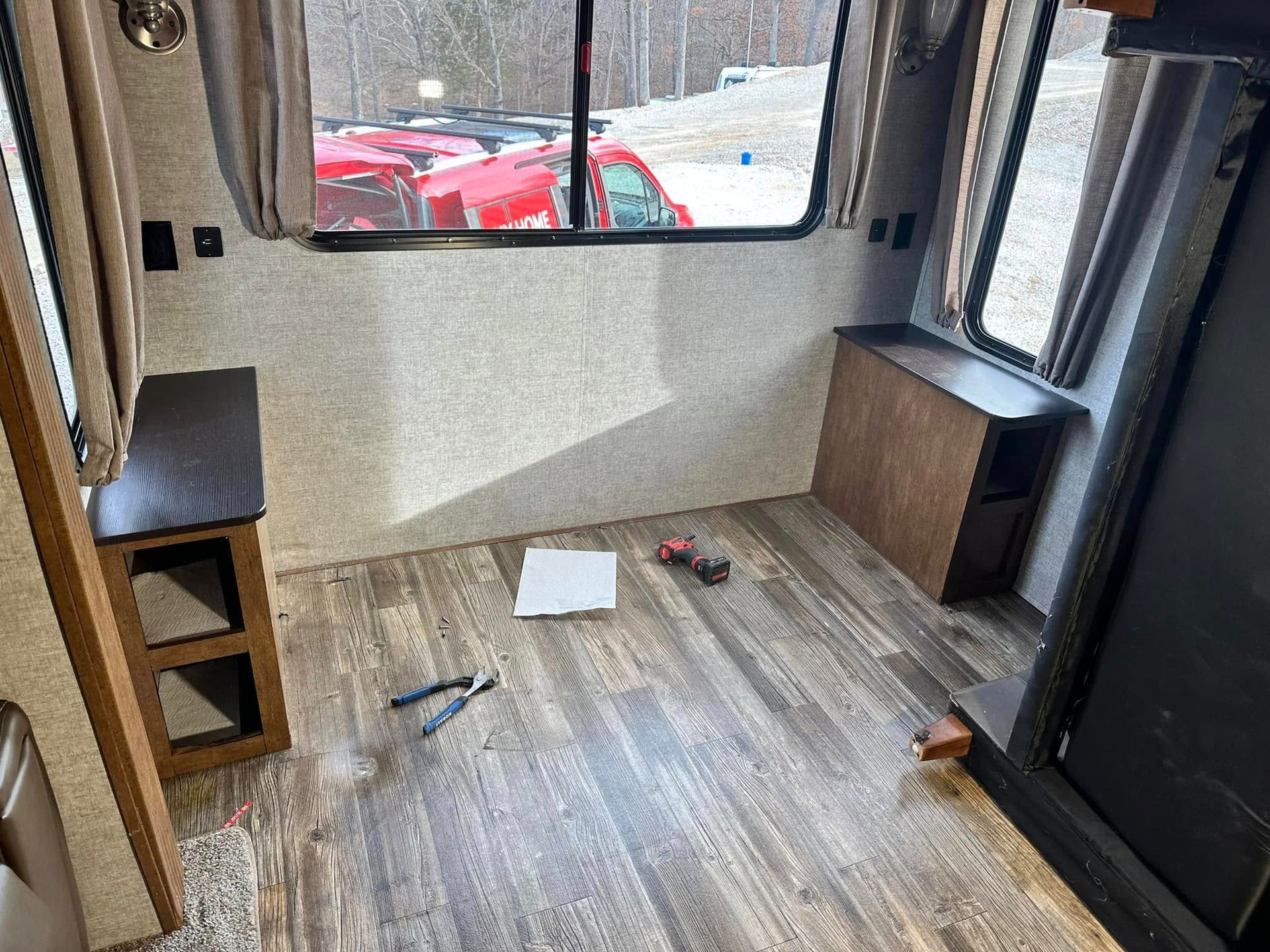 A room in a rv with a wooden floor and a window.