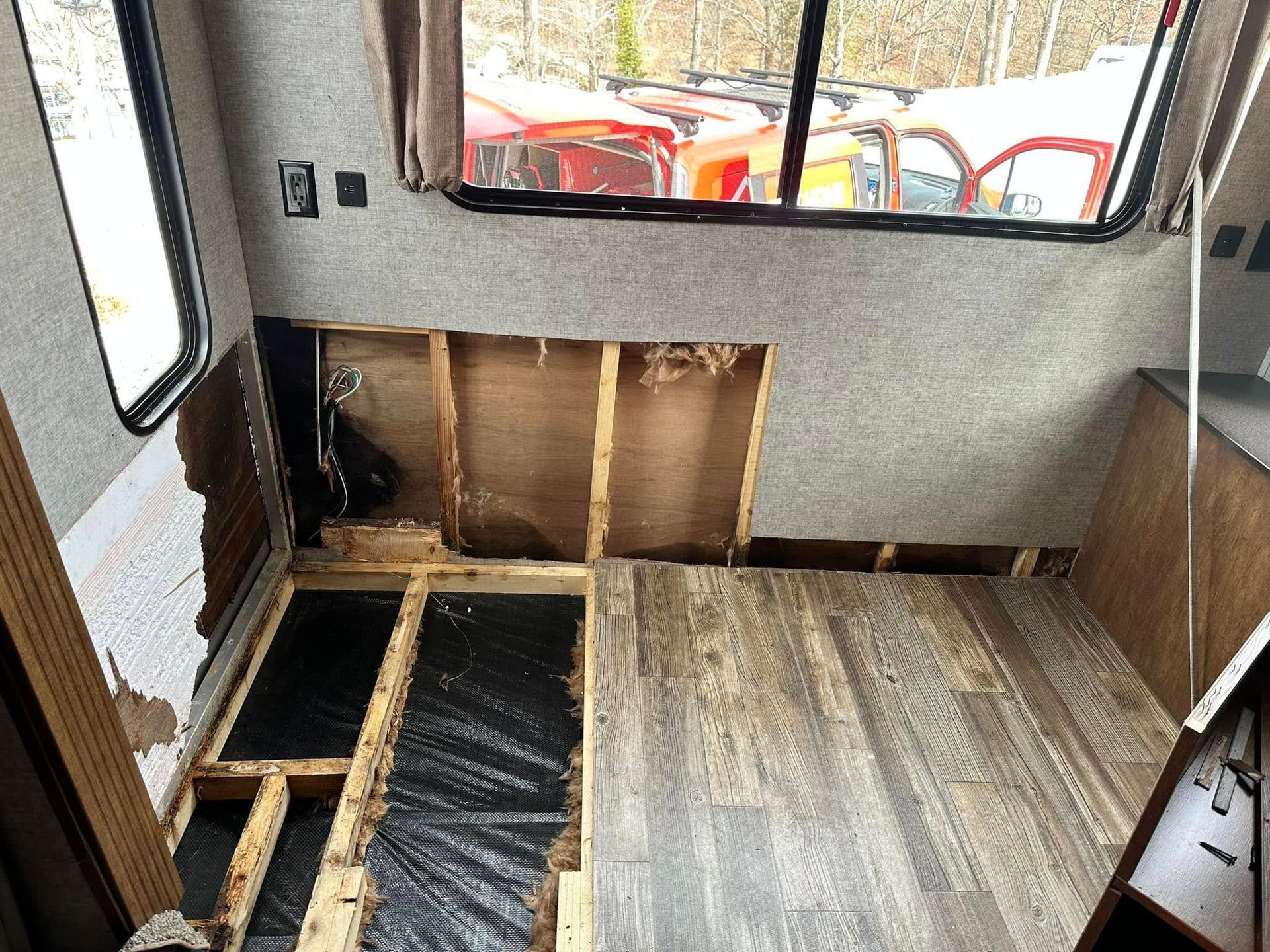 A camper is being remodeled with a wooden floor and a window.