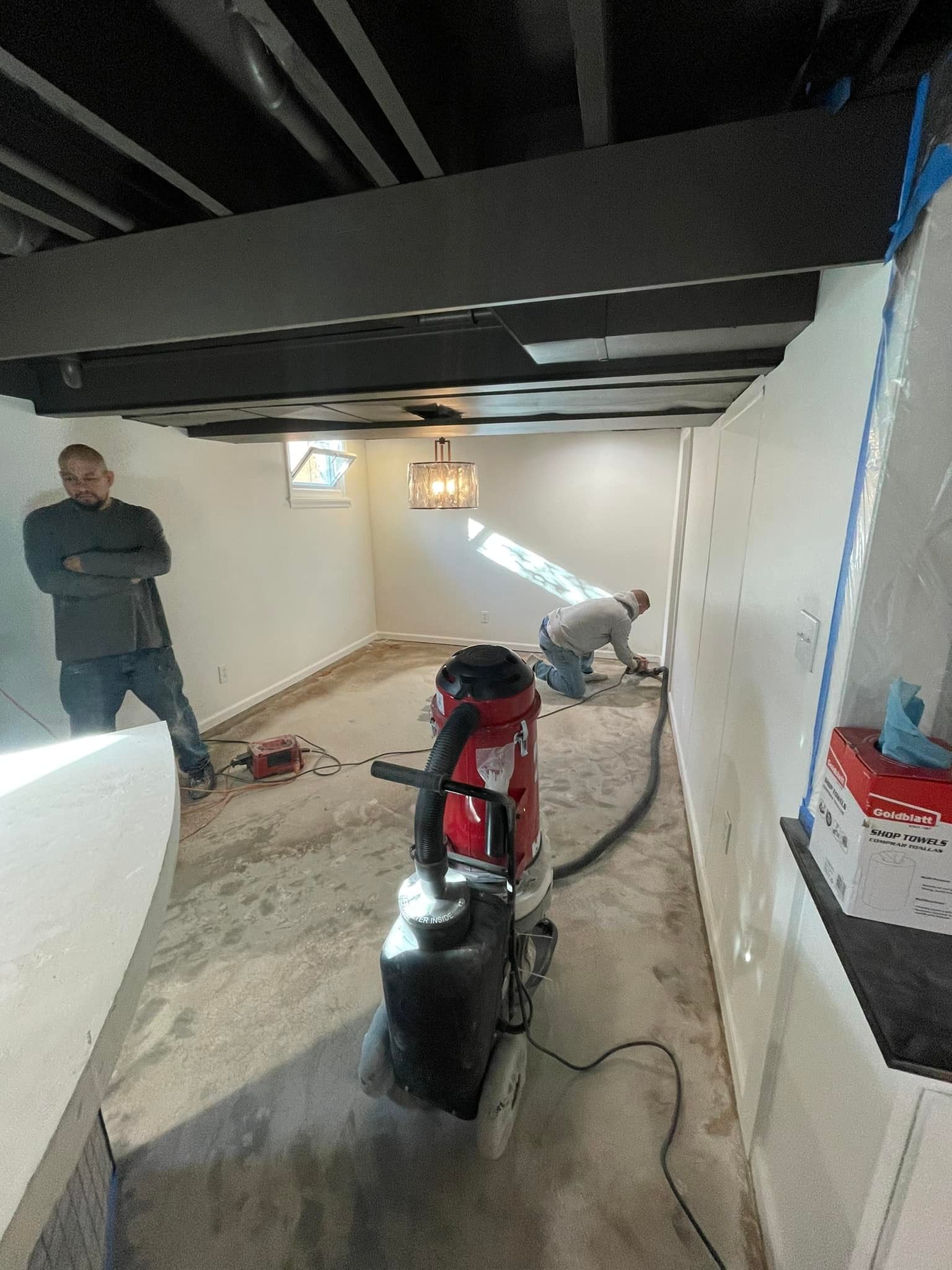 A man is standing next to a vacuum cleaner in a room.