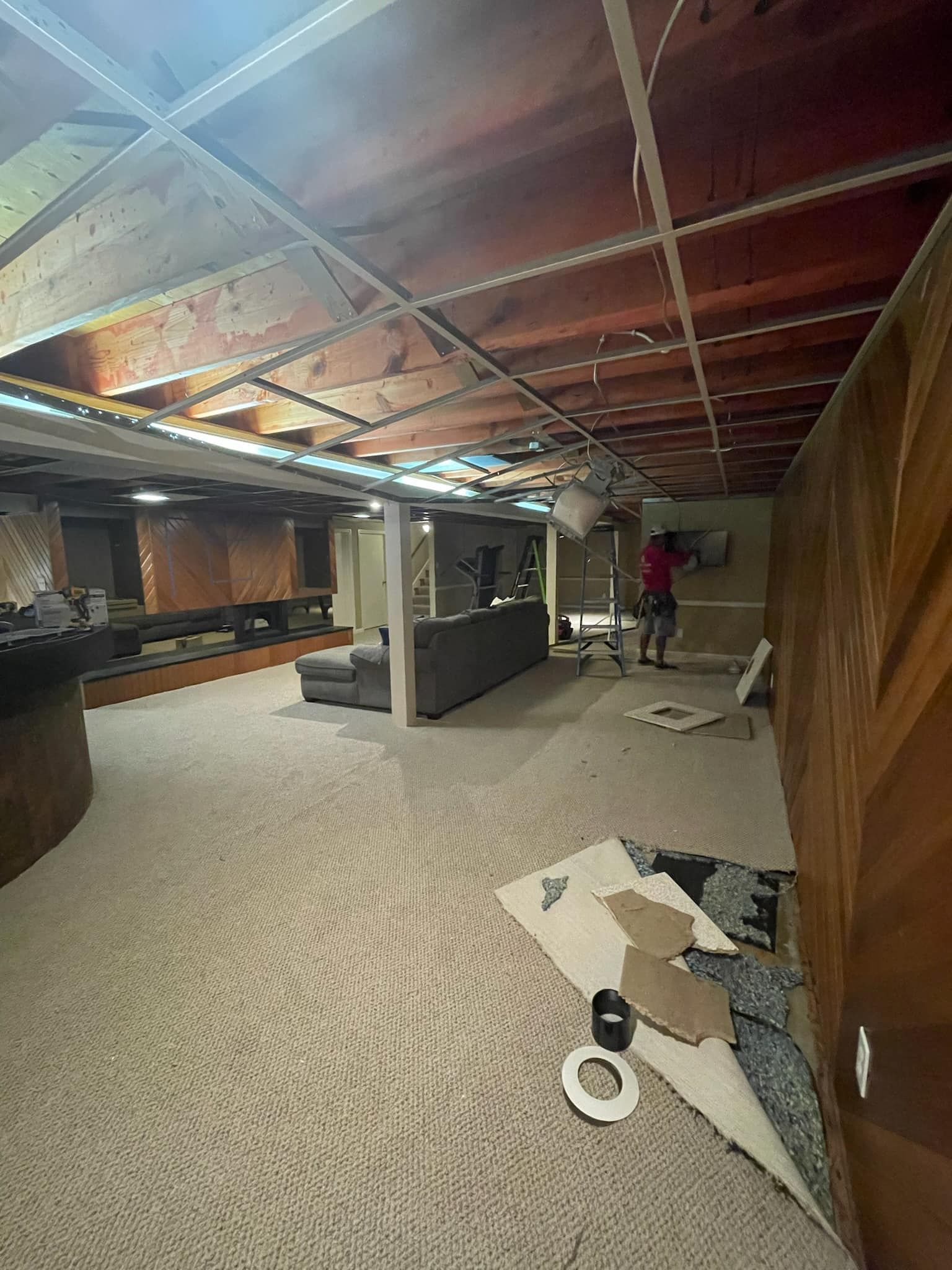 A man is working on the ceiling of a basement.
