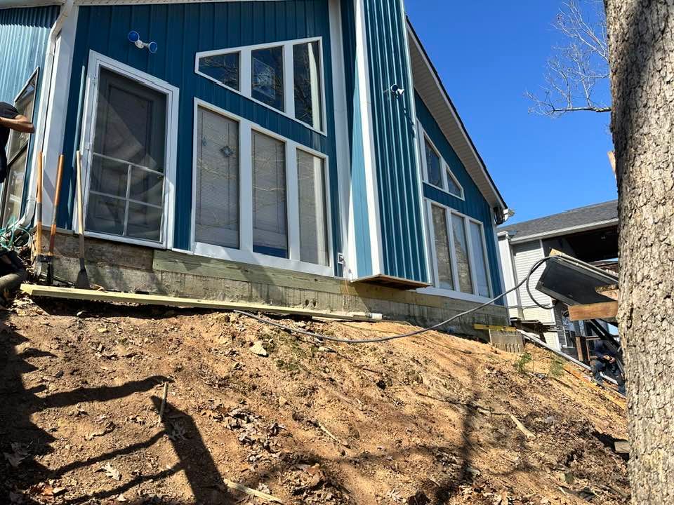 A blue and white house is sitting on top of a dirt hill.