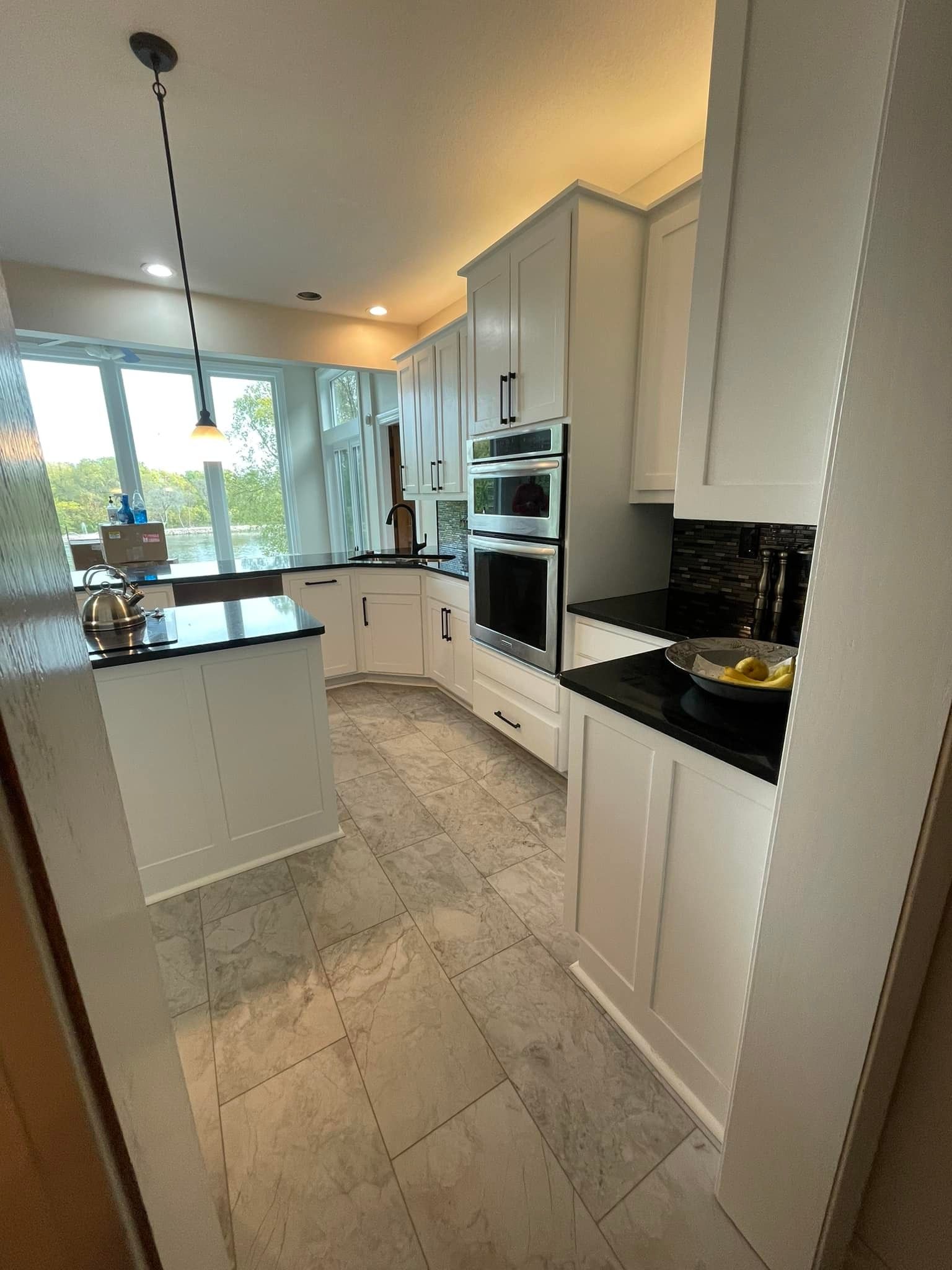 A kitchen with white cabinets , black counter tops , and stainless steel appliances.