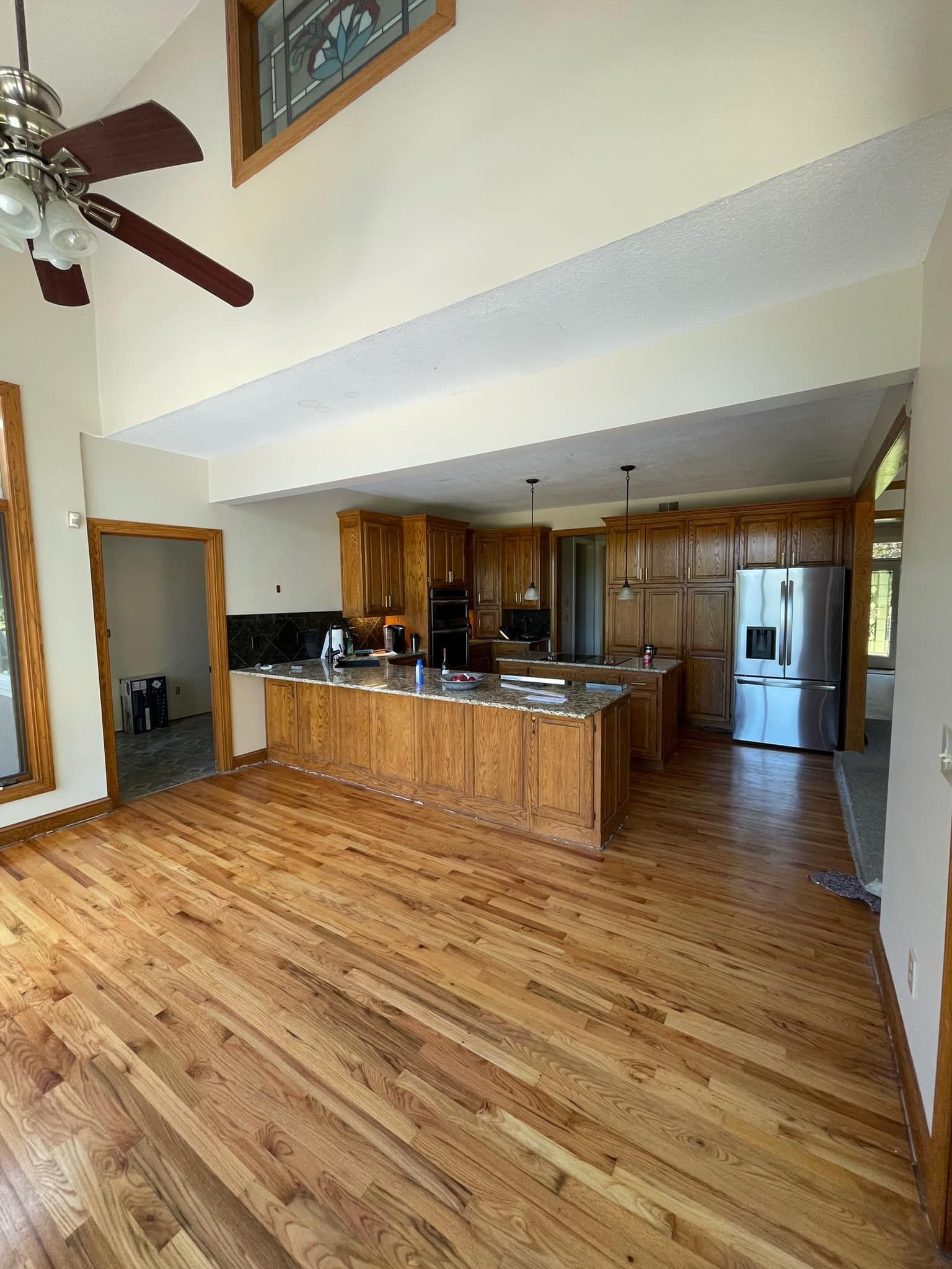 A kitchen with hardwood floors and a ceiling fan.