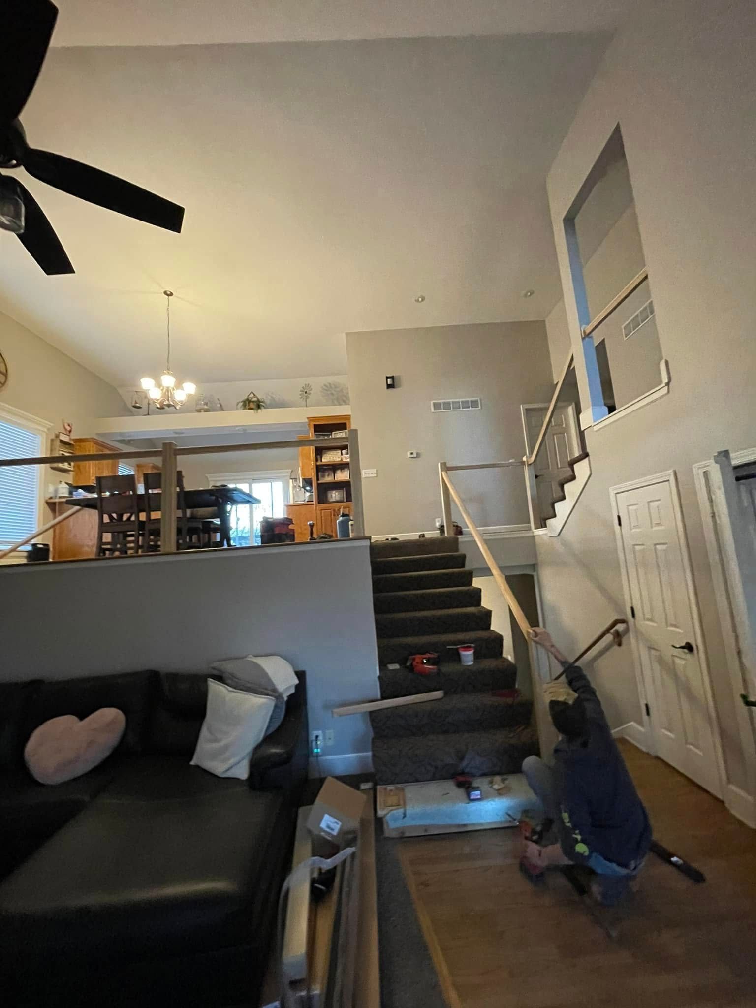 A man is working on a staircase in a living room.