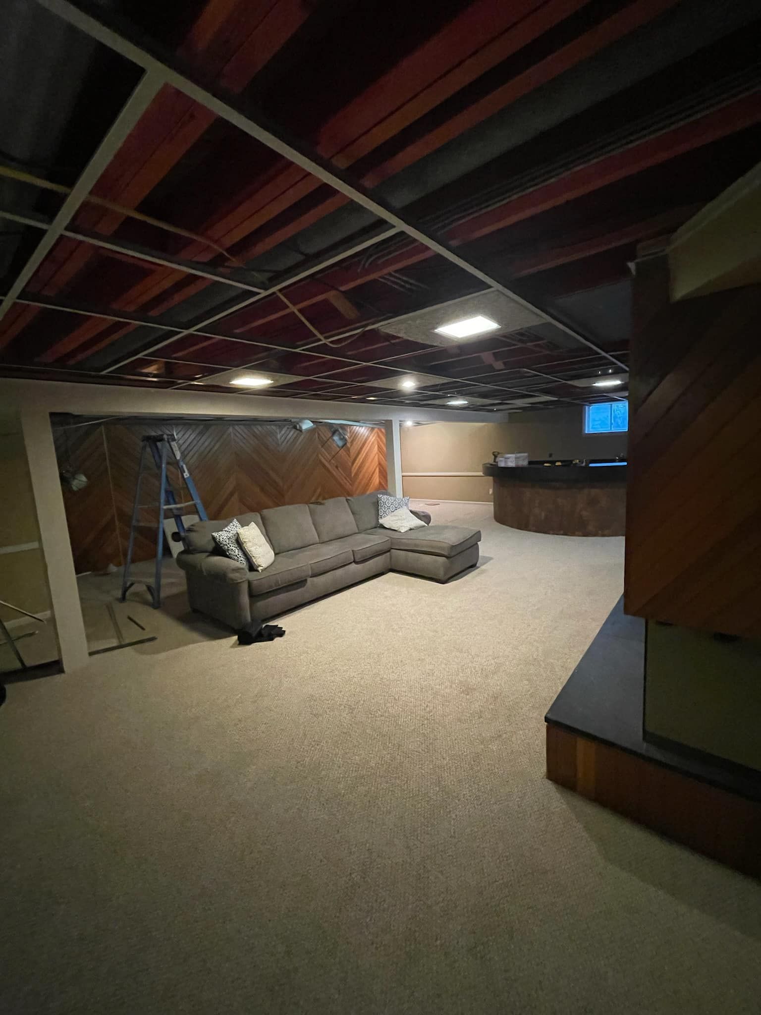 A living room in a basement with a couch and a television.
