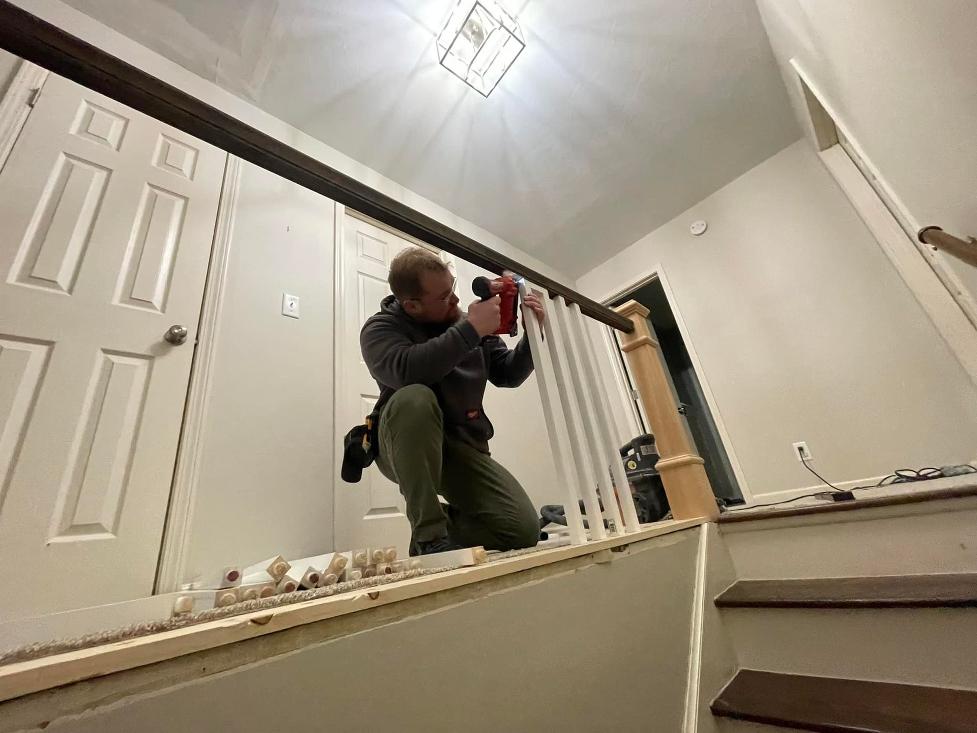A man is installing a railing on a set of stairs.