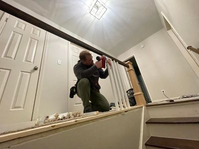 A man is installing a railing on a set of stairs.