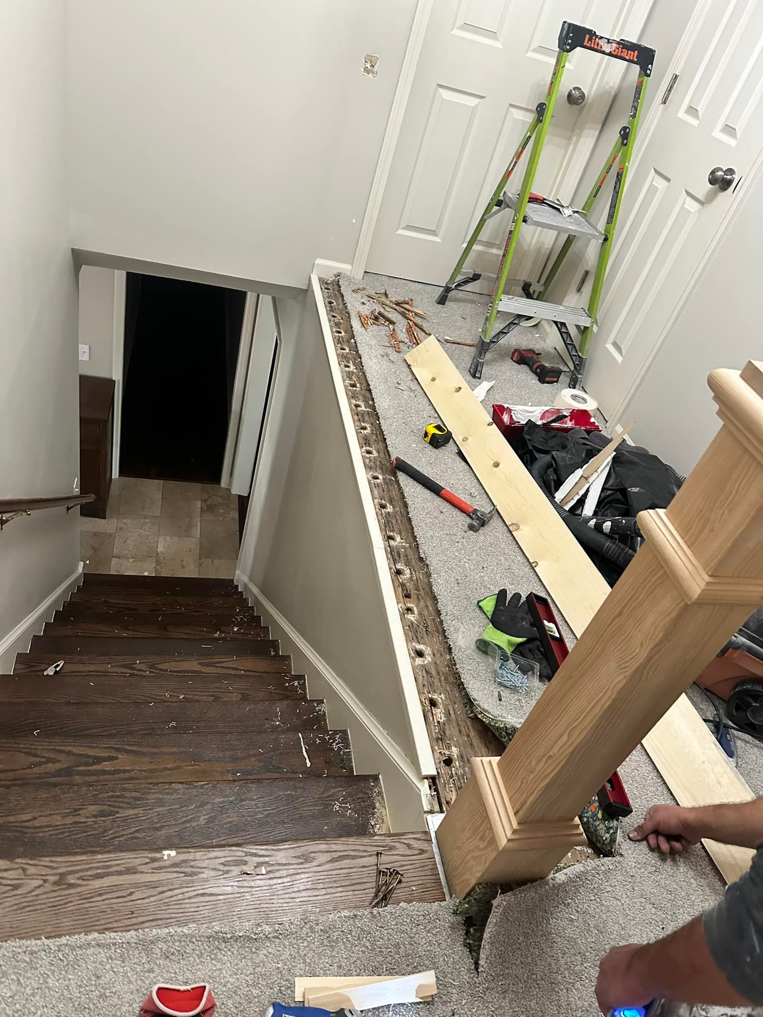 A man is working on a wooden staircase in a house.
