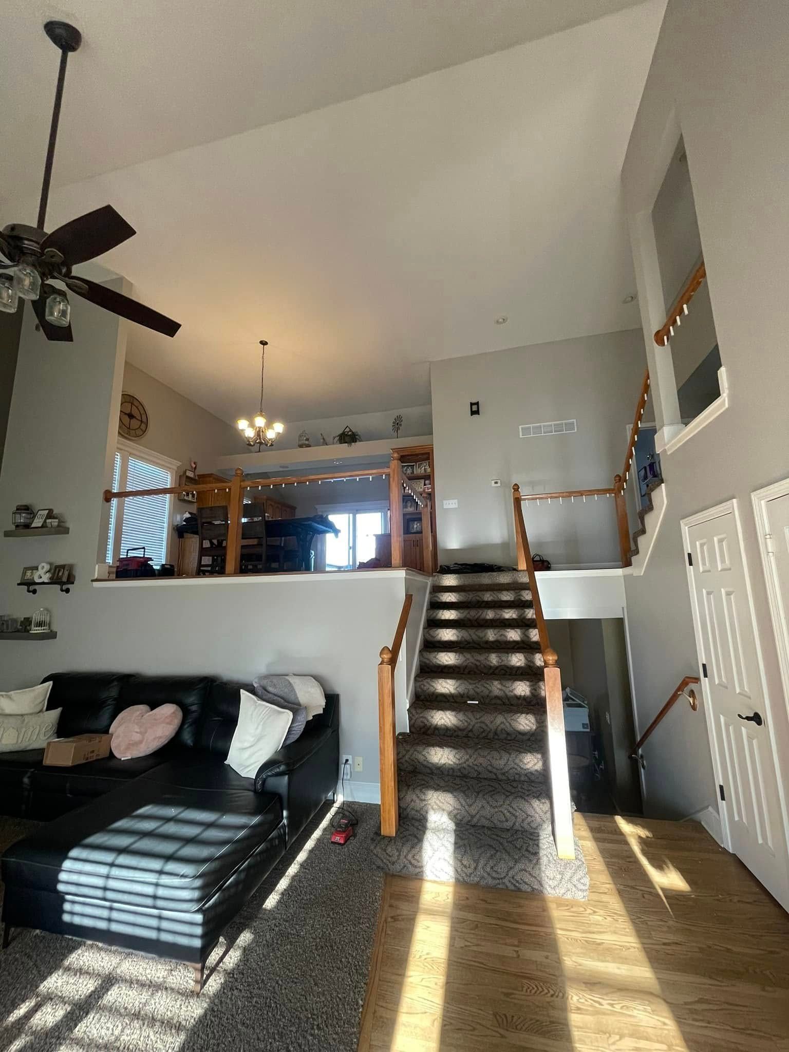 A living room with a couch , stairs and a ceiling fan.