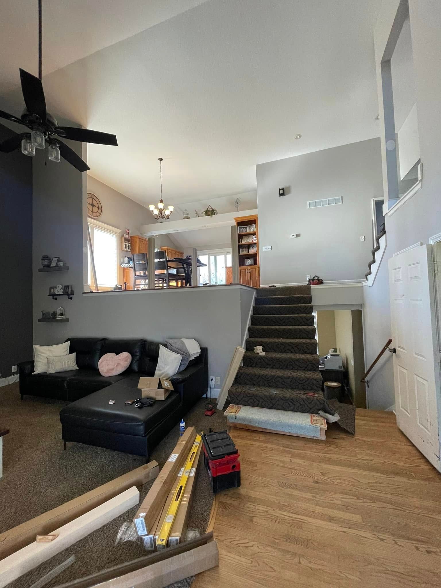 A living room with a couch , stairs and a ceiling fan.