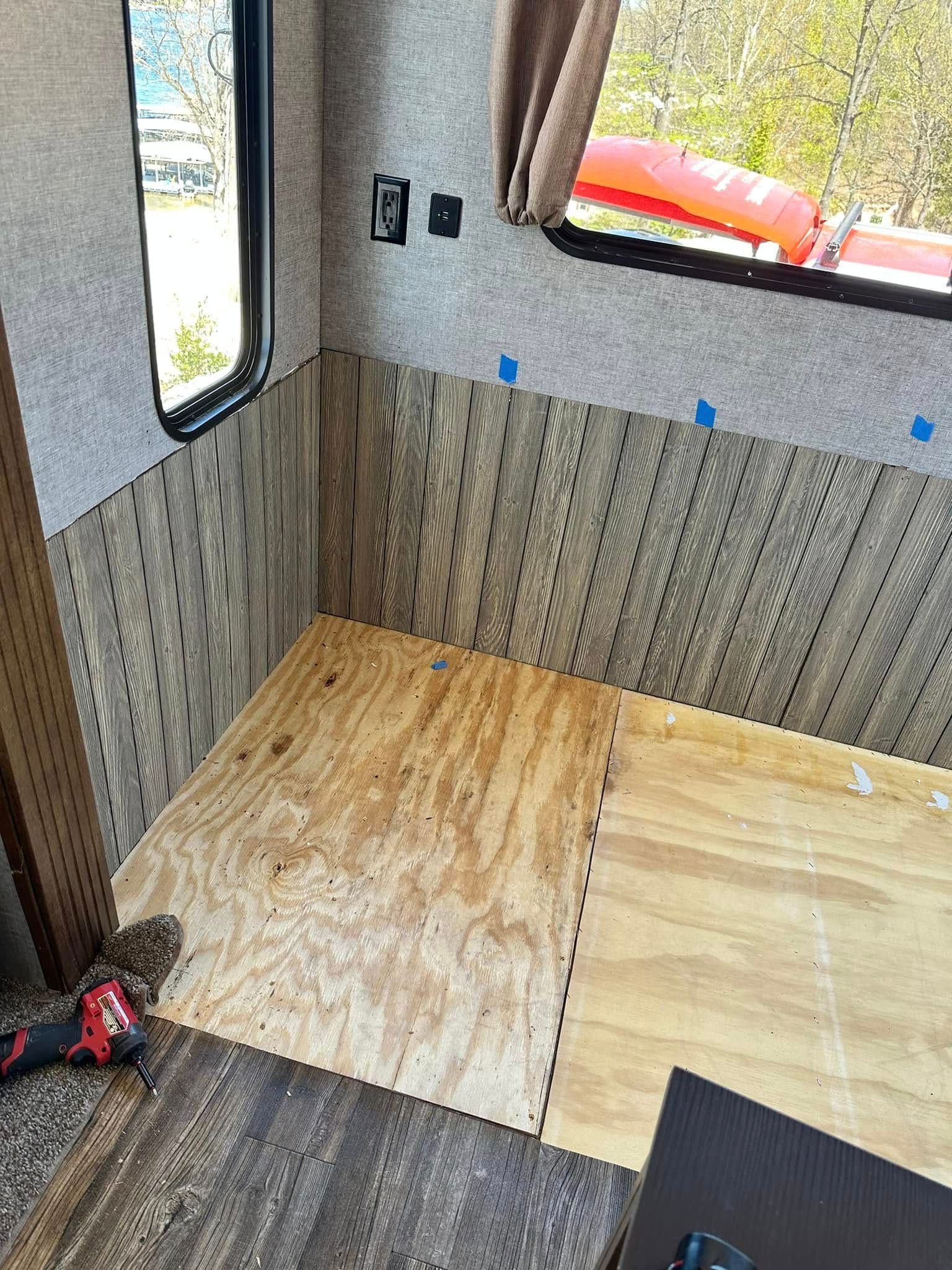 A room in a rv with a wooden floor and a window.