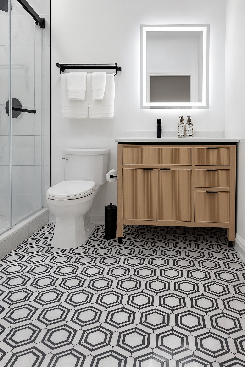 Bathroom with patterned tile floor, glass shower, wooden vanity, and backlit mirror.