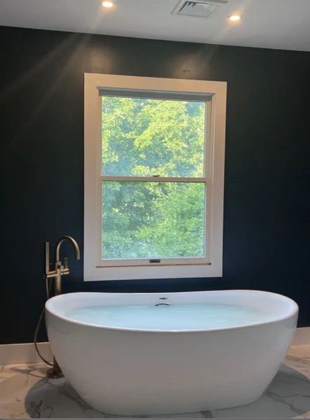 A bathtub in a bathroom next to a window A bathtub in a bathroom next to a window