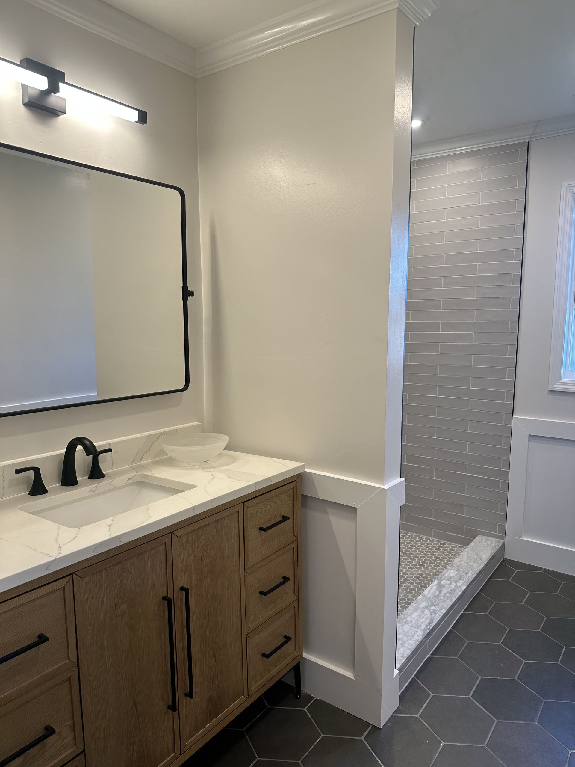A bathroom with a sink , mirror and walk in shower.