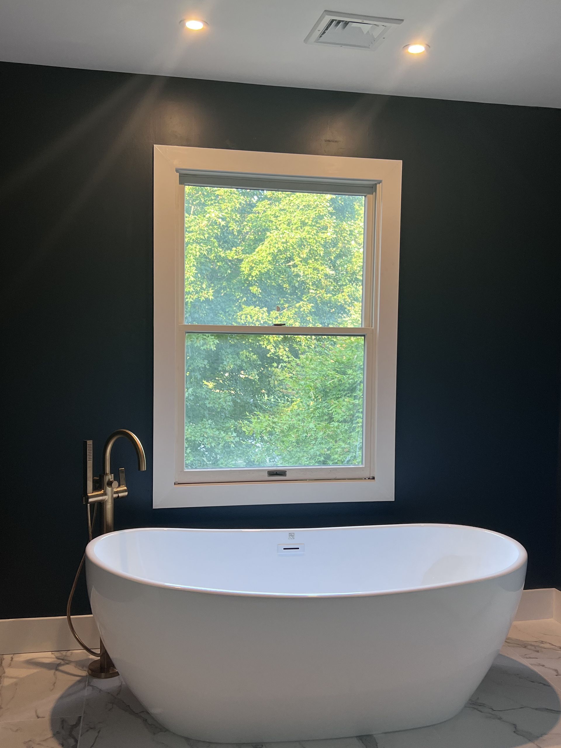 A bathtub in a bathroom next to a window.