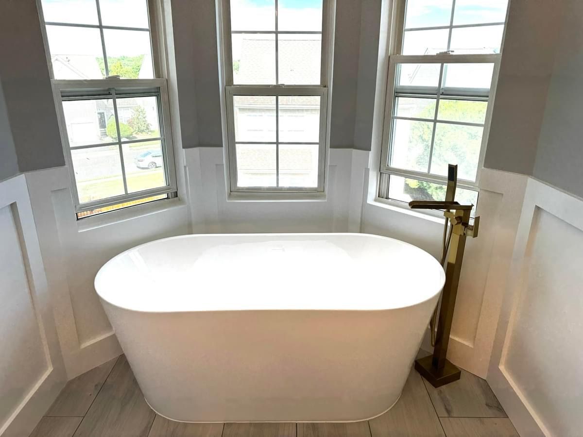 A white bathtub is sitting in a bathroom next to a window.