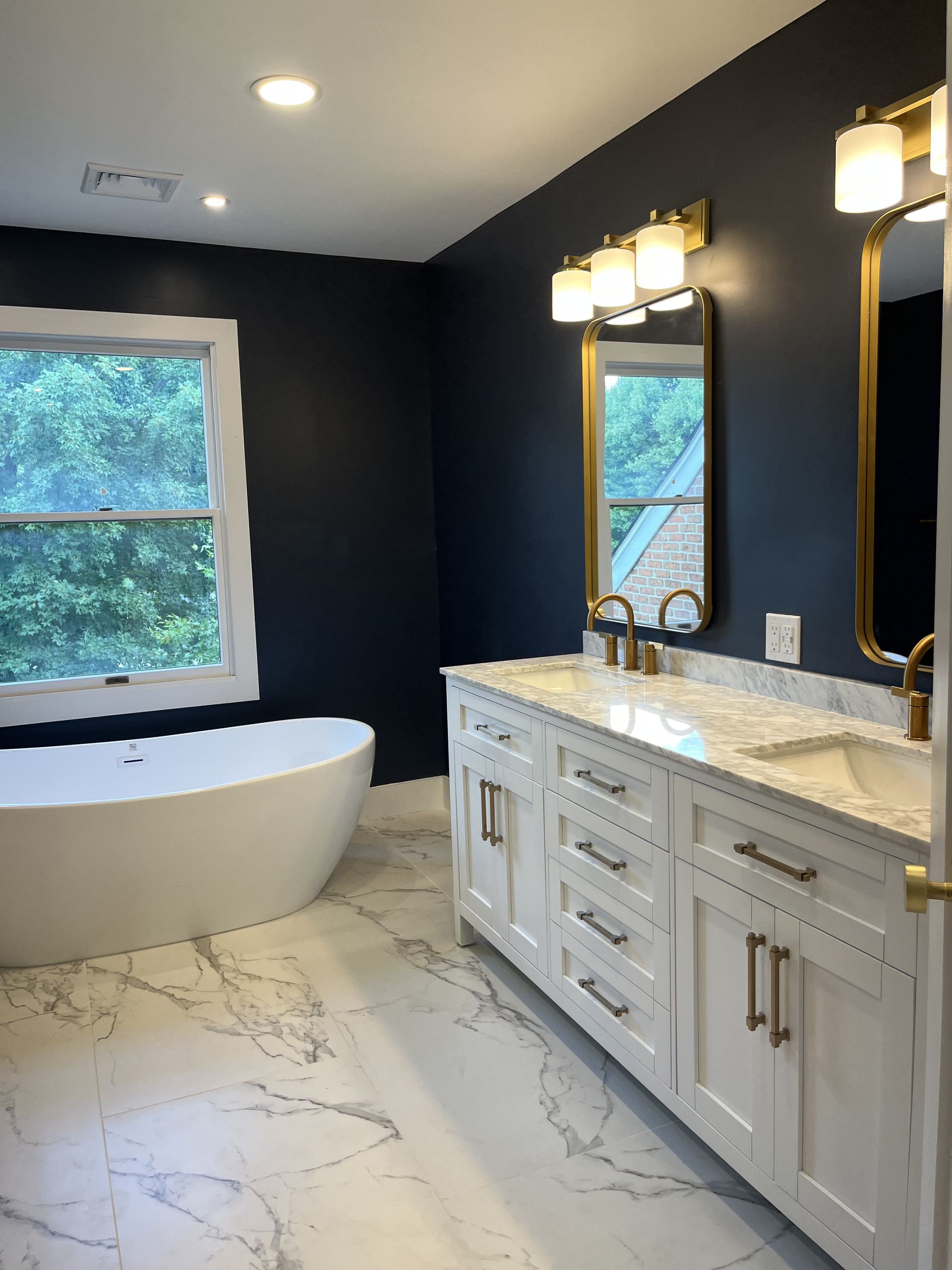 A bathroom with a tub, sink, mirror, and window.