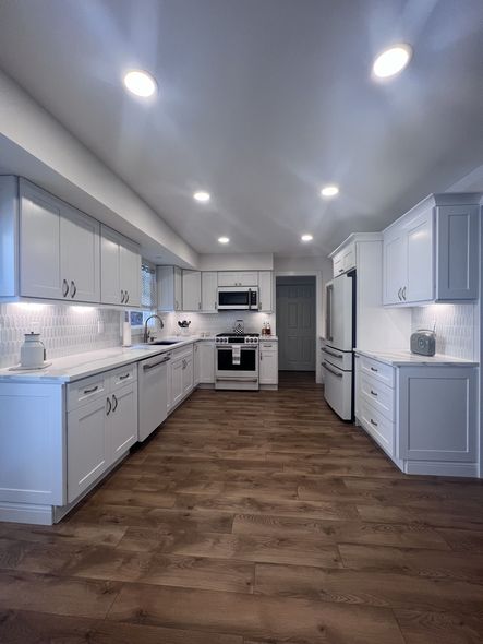 A kitchen with white cabinets and wooden floors. A kitchen with white cabinets and wooden floors.