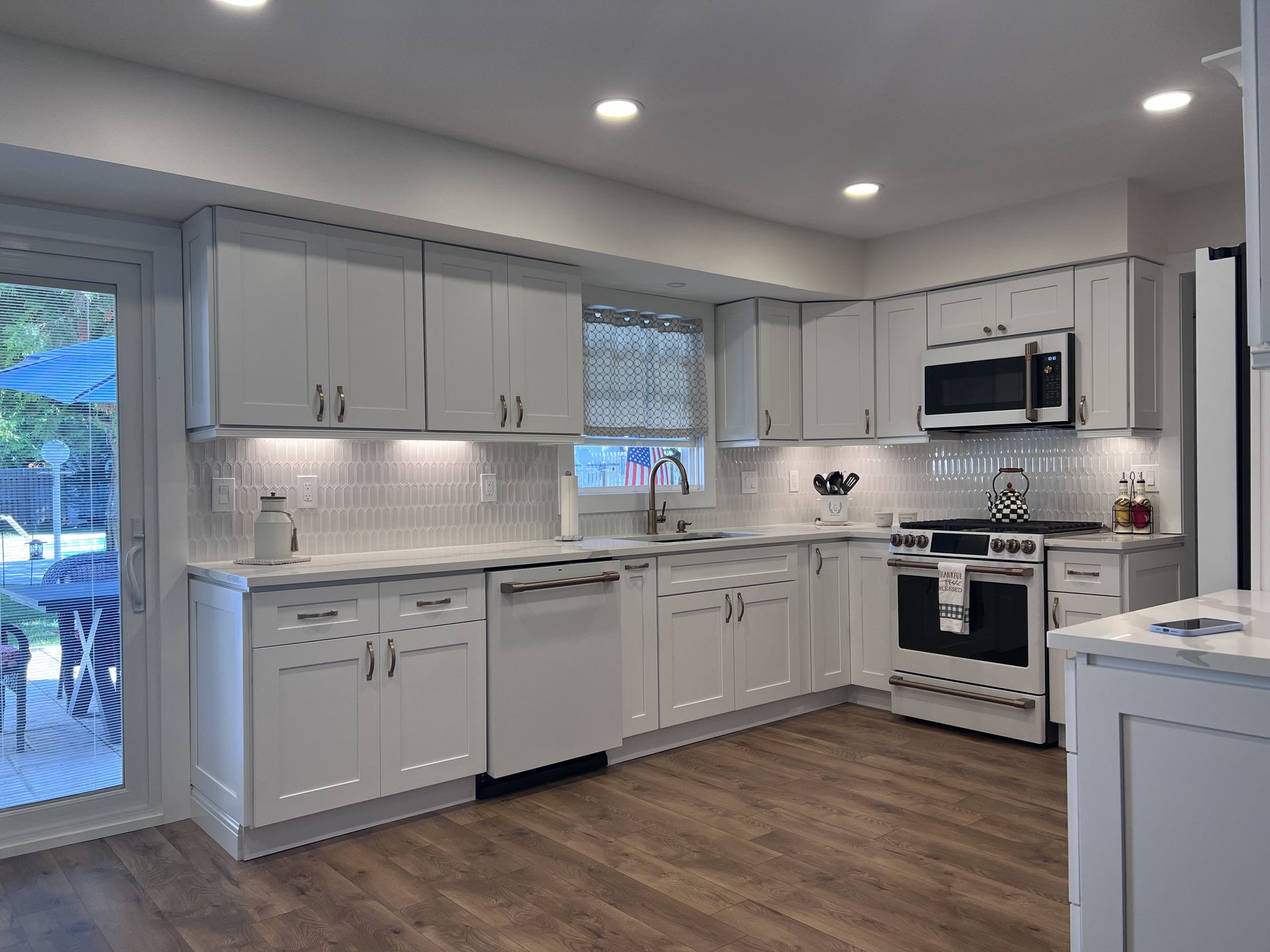 A kitchen with white cabinets , stainless steel appliances , and hardwood floors.