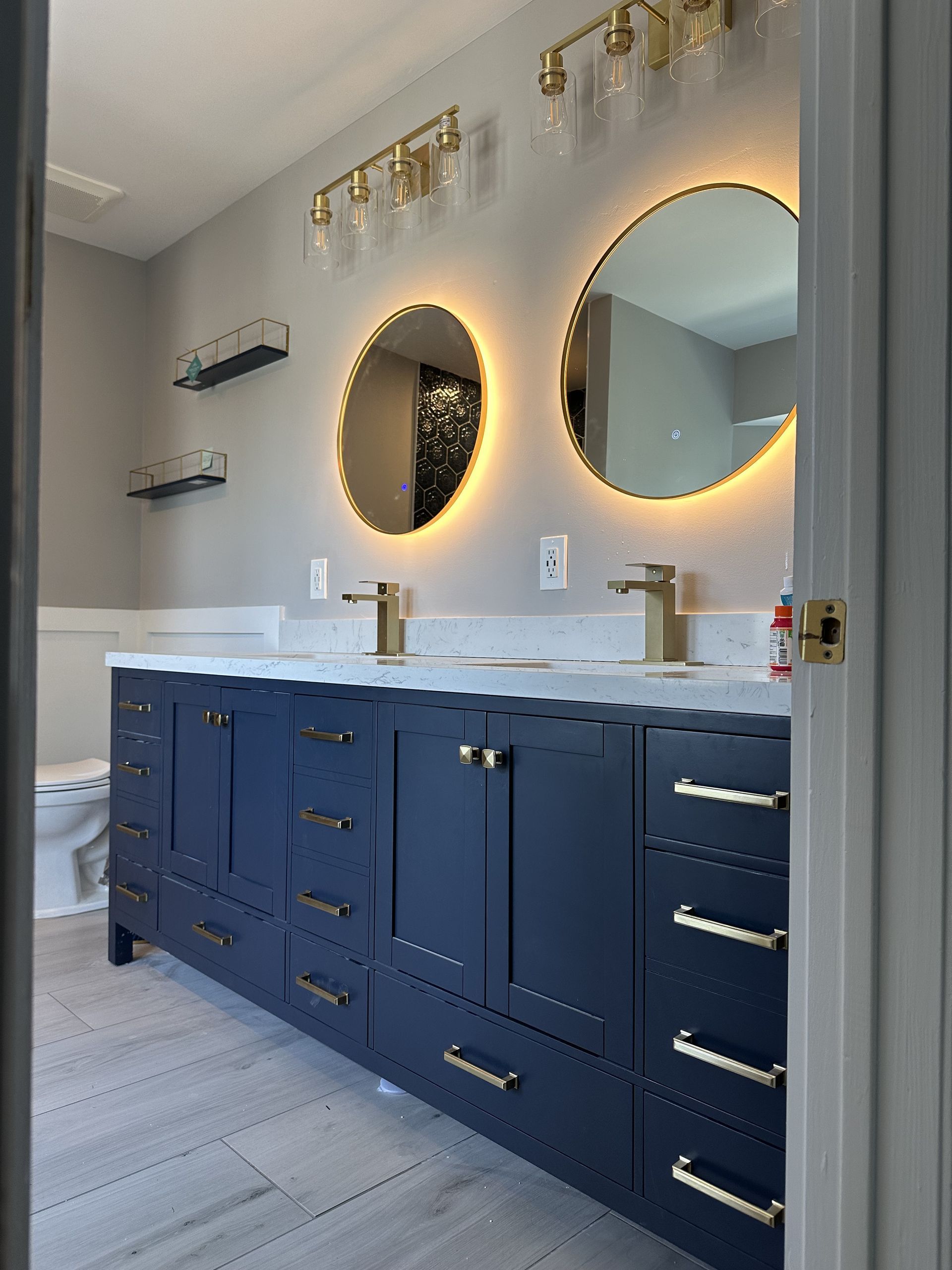 A bathroom with two sinks , two mirrors and a toilet.