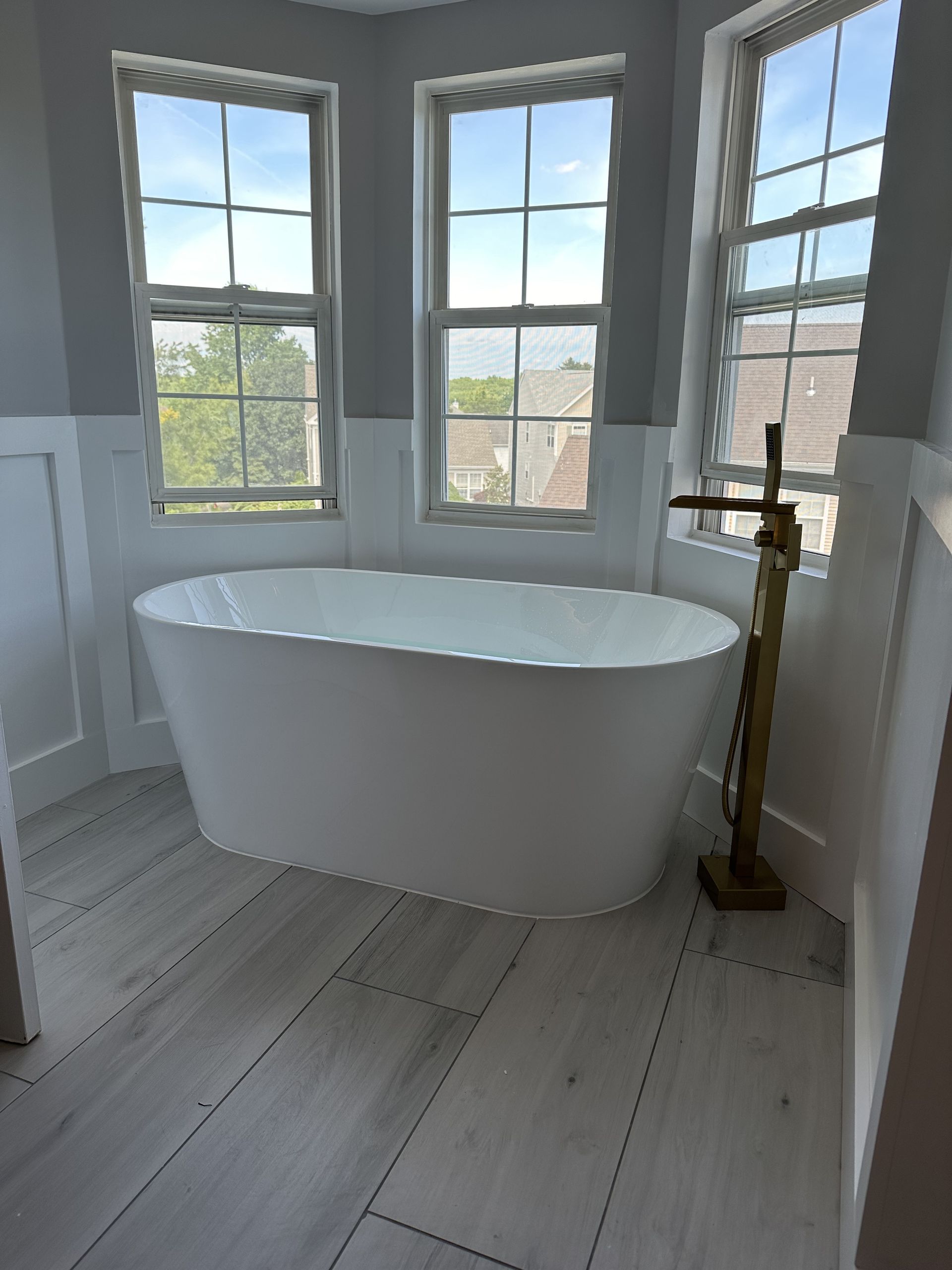 A bathroom with a bathtub and two windows.