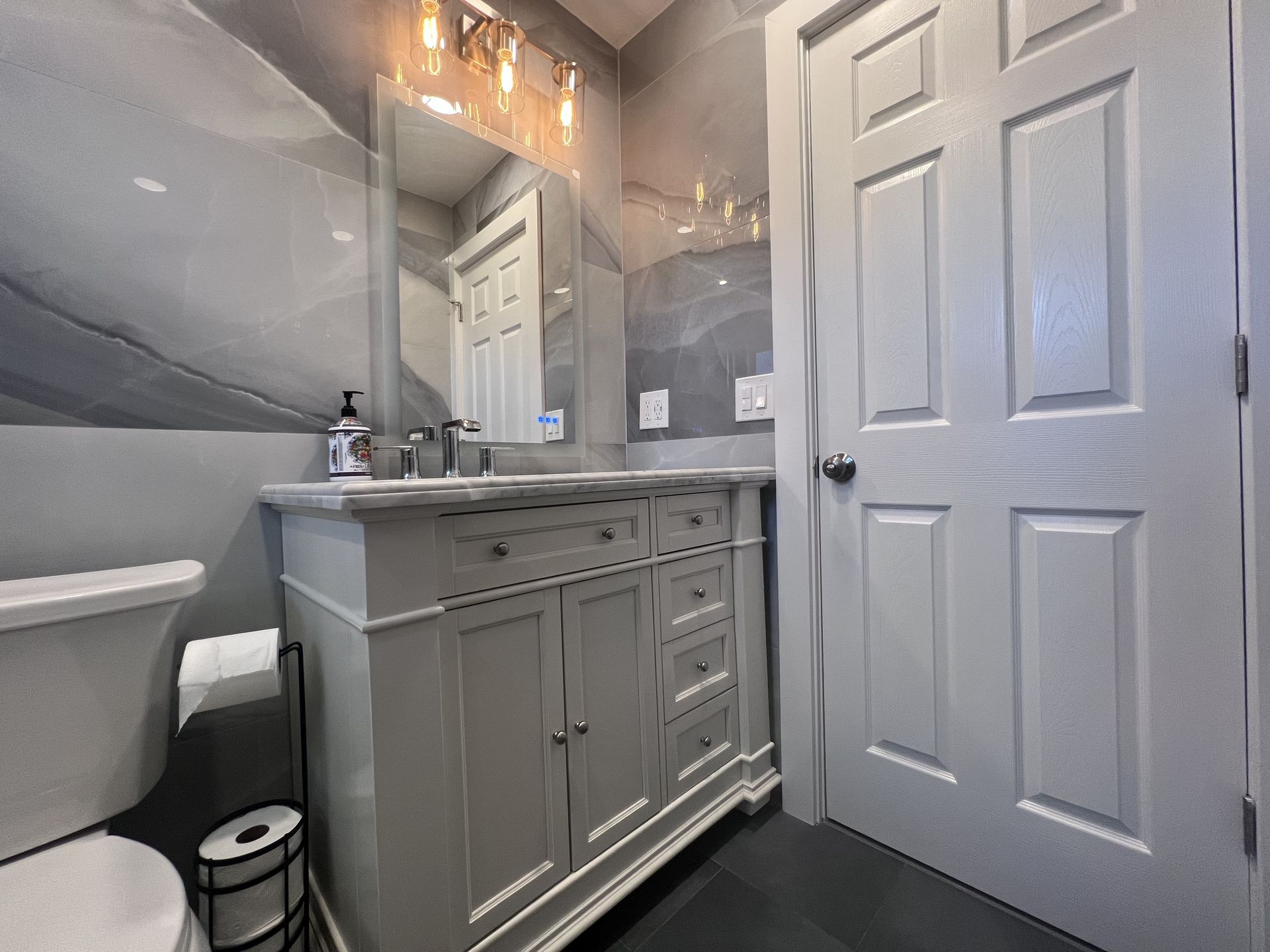 A bathroom with a sink, toilet, and mirror.