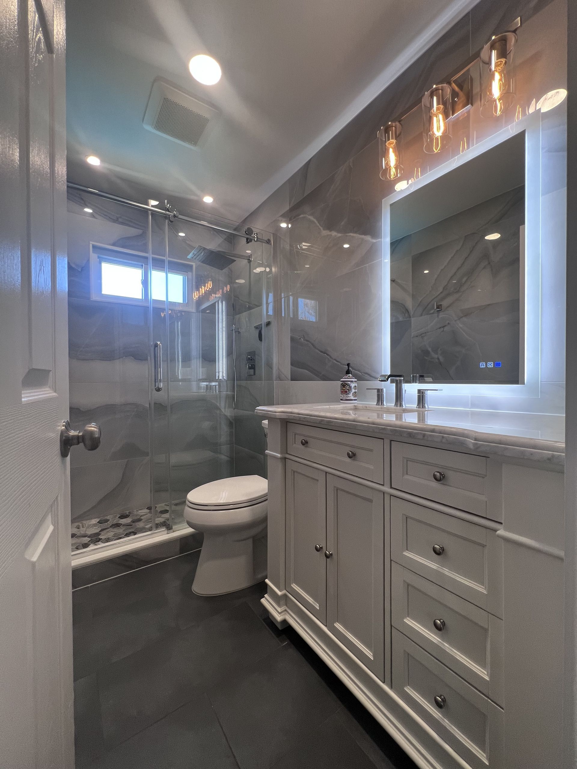 A bathroom with a toilet a sink and a mirror.