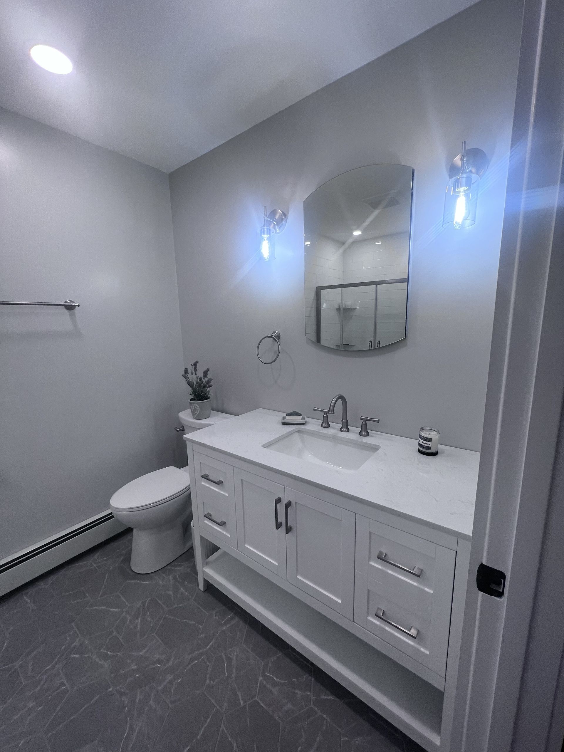 A bathroom with a sink, toilet, and mirror.
