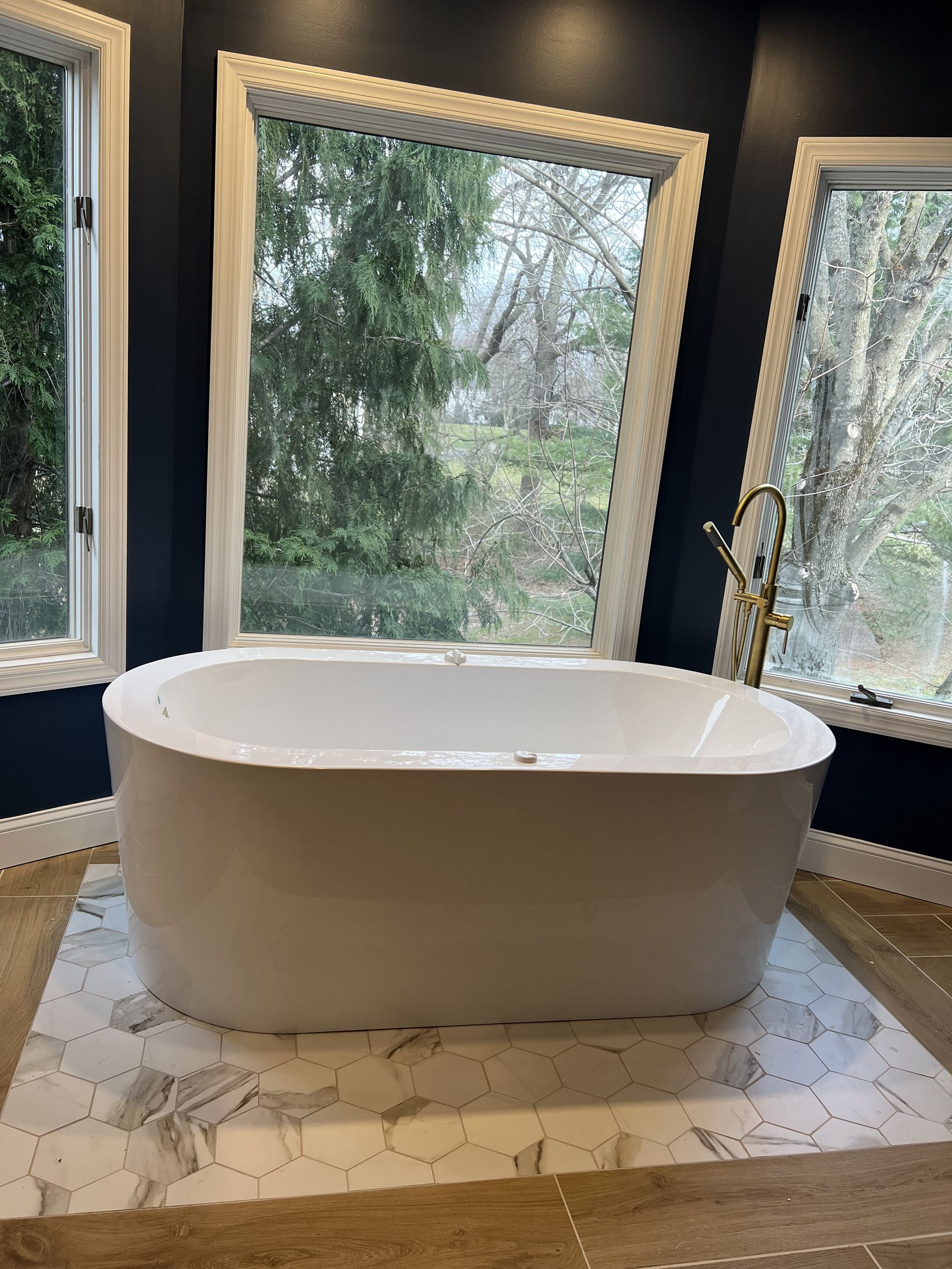A white bathtub is sitting in a bathroom next to a window.