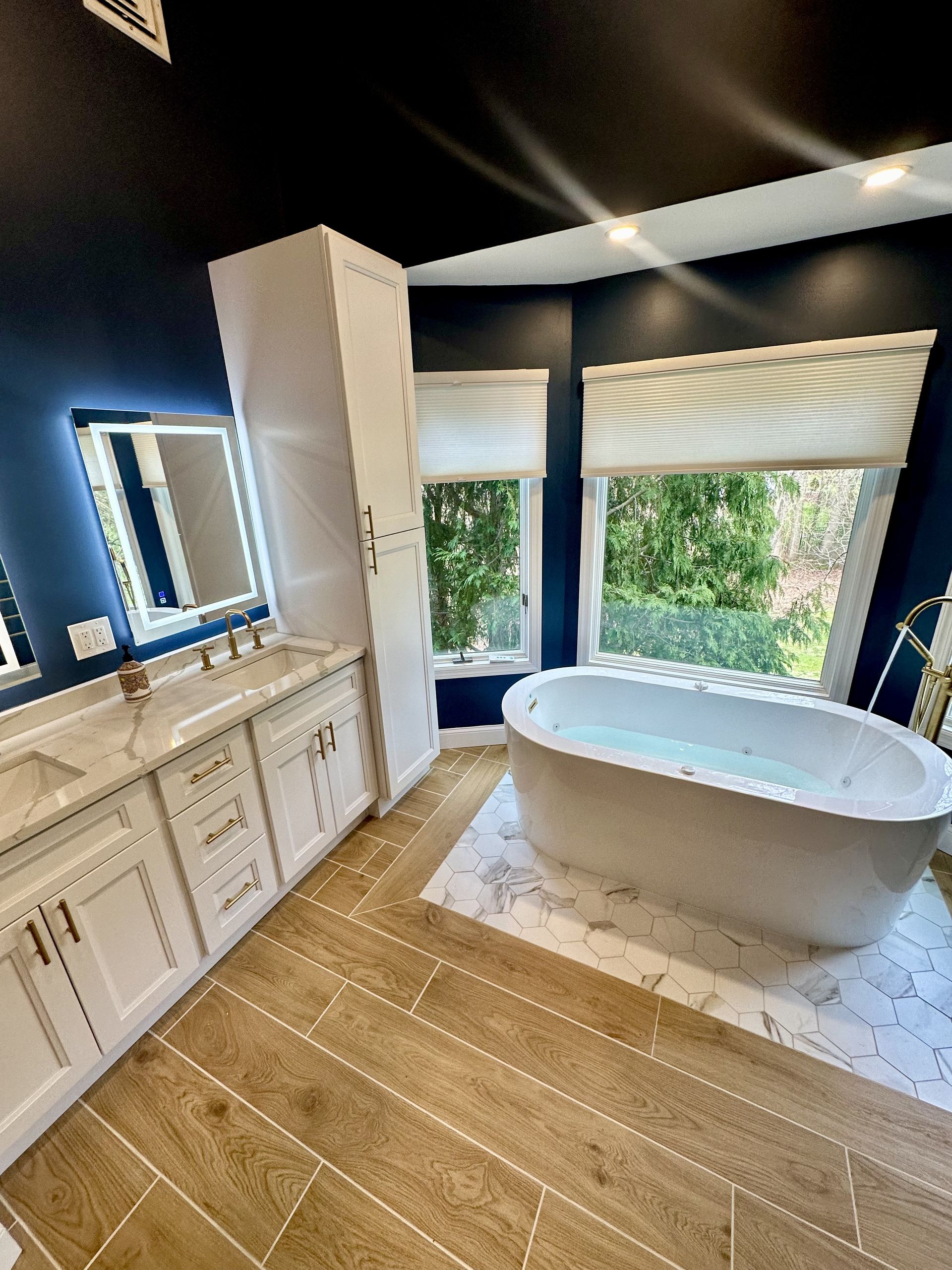 A bathroom with a tub , sink , mirror and window.
