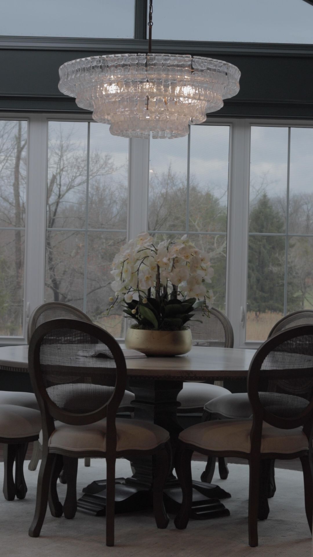 A dining room with a table and chairs and a chandelier hanging from the ceiling.