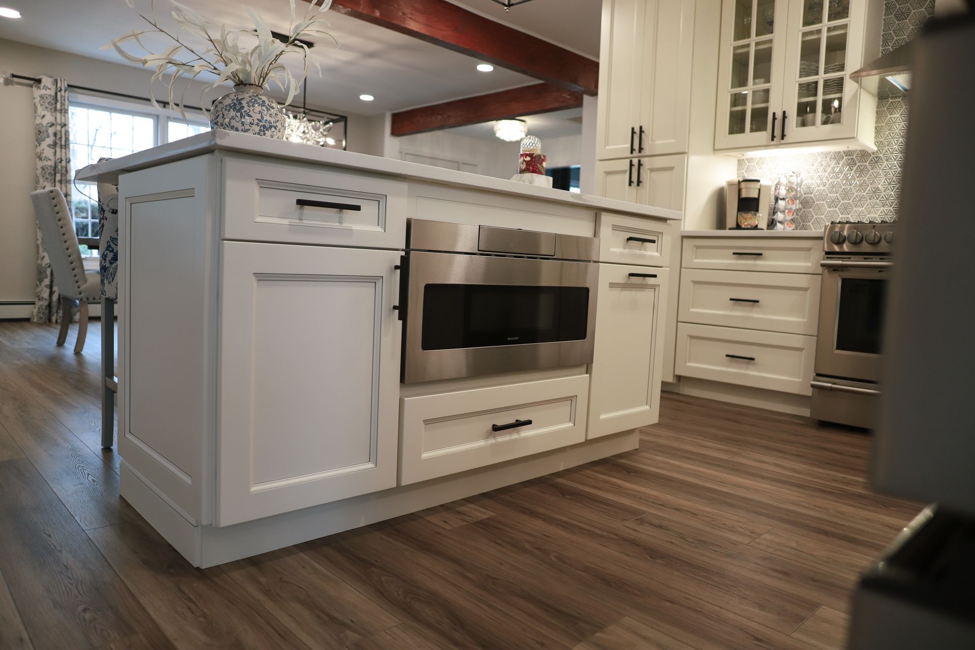 A kitchen with white cabinets, stainless steel appliances and a large island.