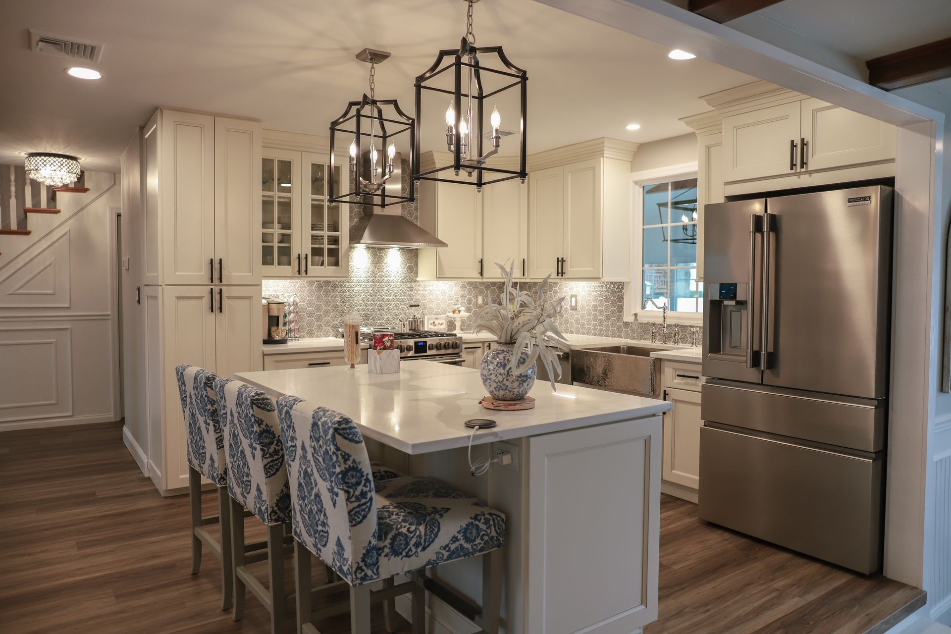 A kitchen with white cabinets , stainless steel appliances , and a large island.