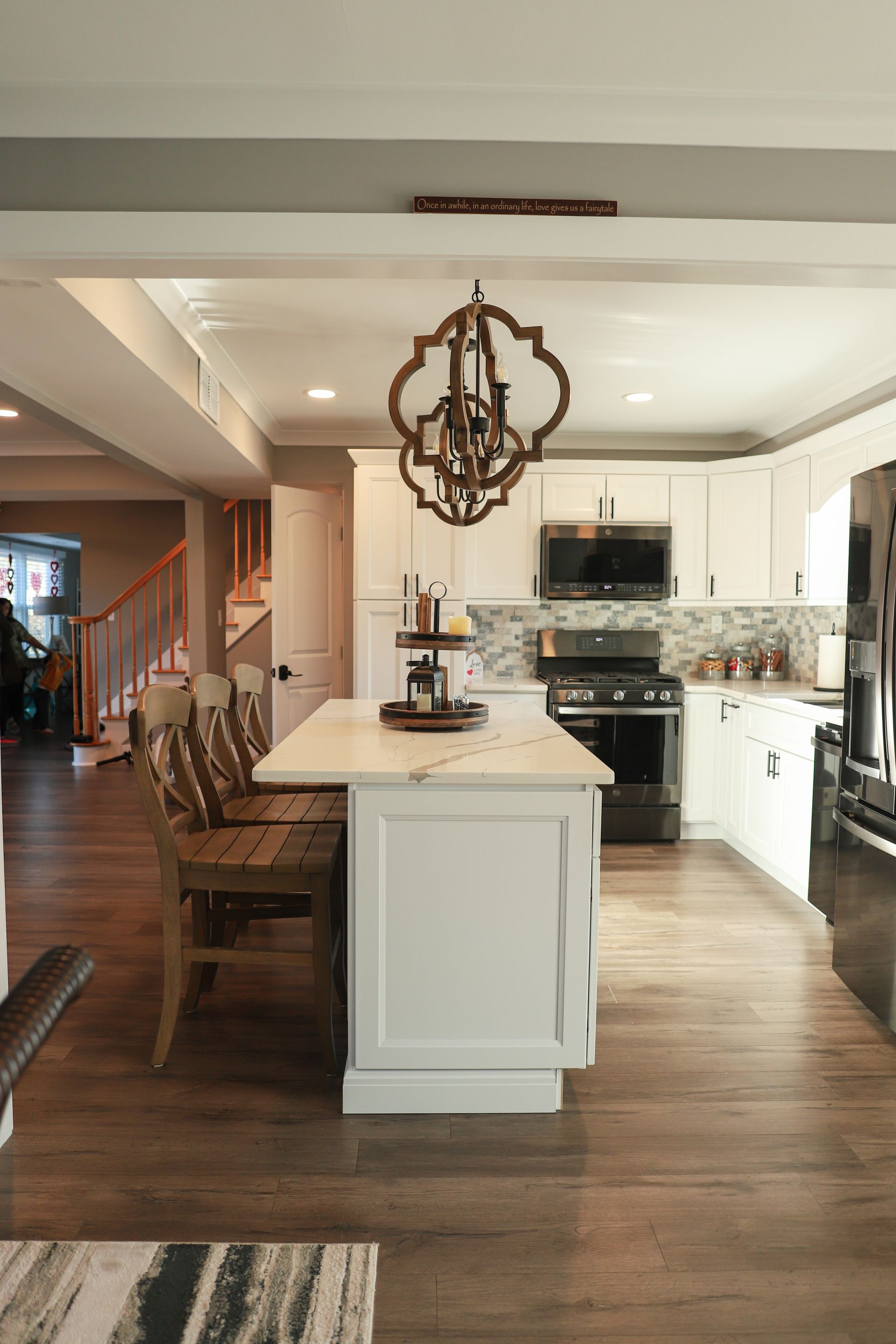 A kitchen with white cabinets, stainless steel appliances, and a large island with a table and chairs.