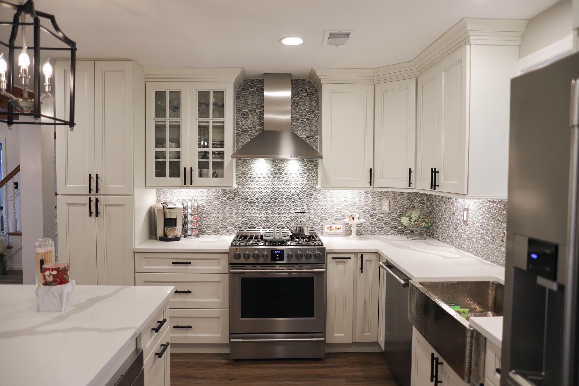 A kitchen with white cabinets, granite counter tops, stainless steel appliances, and a large island.