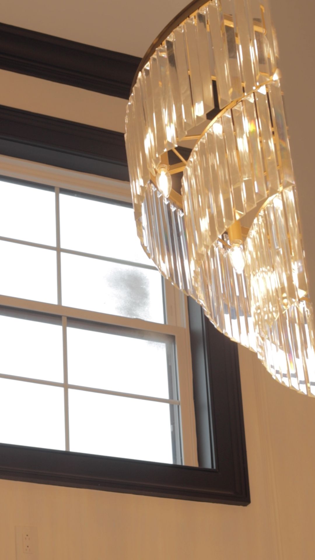 A chandelier is hanging from the ceiling in front of a window.