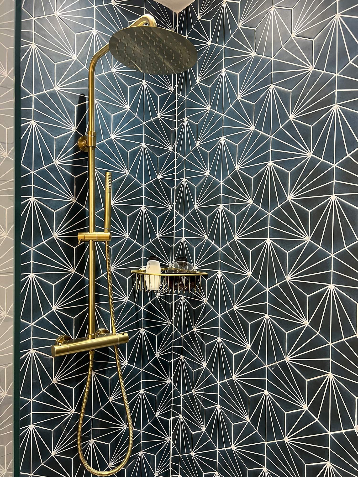 A shower head in a bathroom with a patterned wall