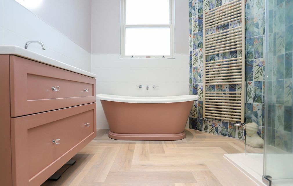 A bathroom with a bathtub , sink , and towel rack.