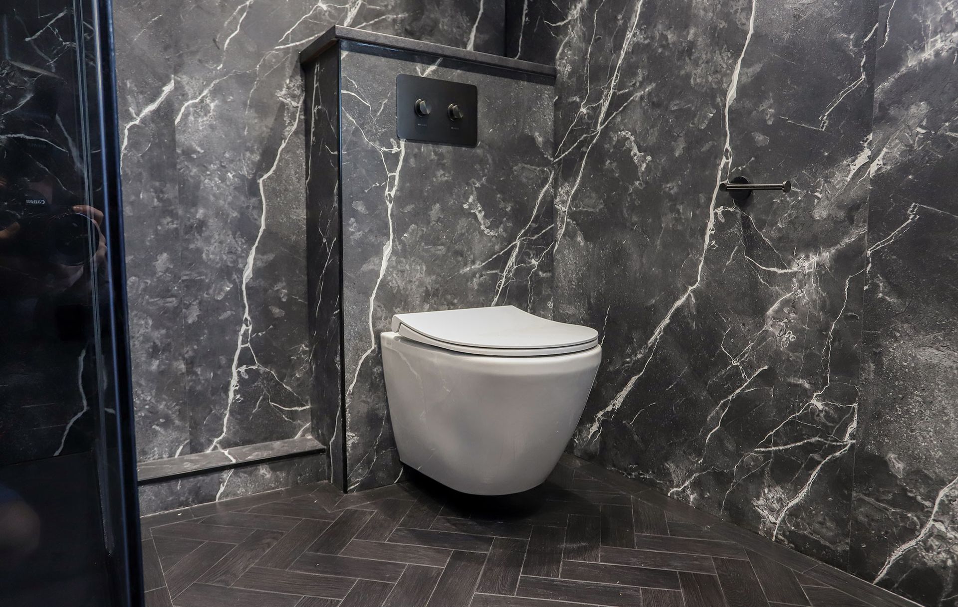 A wall mounted toilet in a bathroom with marble walls