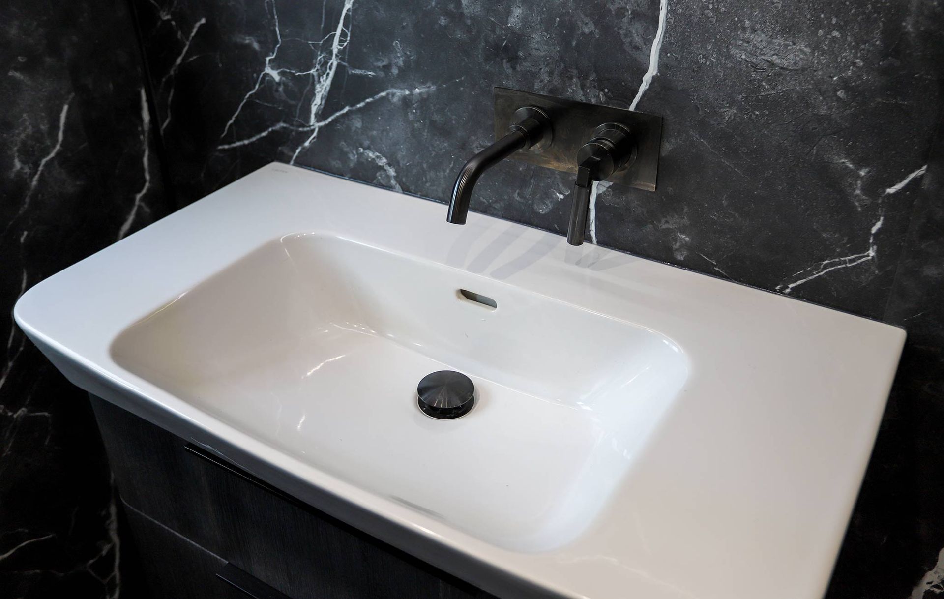 A bathroom sink with a black marble wall behind it