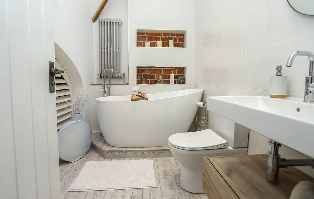 A bathroom with a tub , toilet , sink and mirror