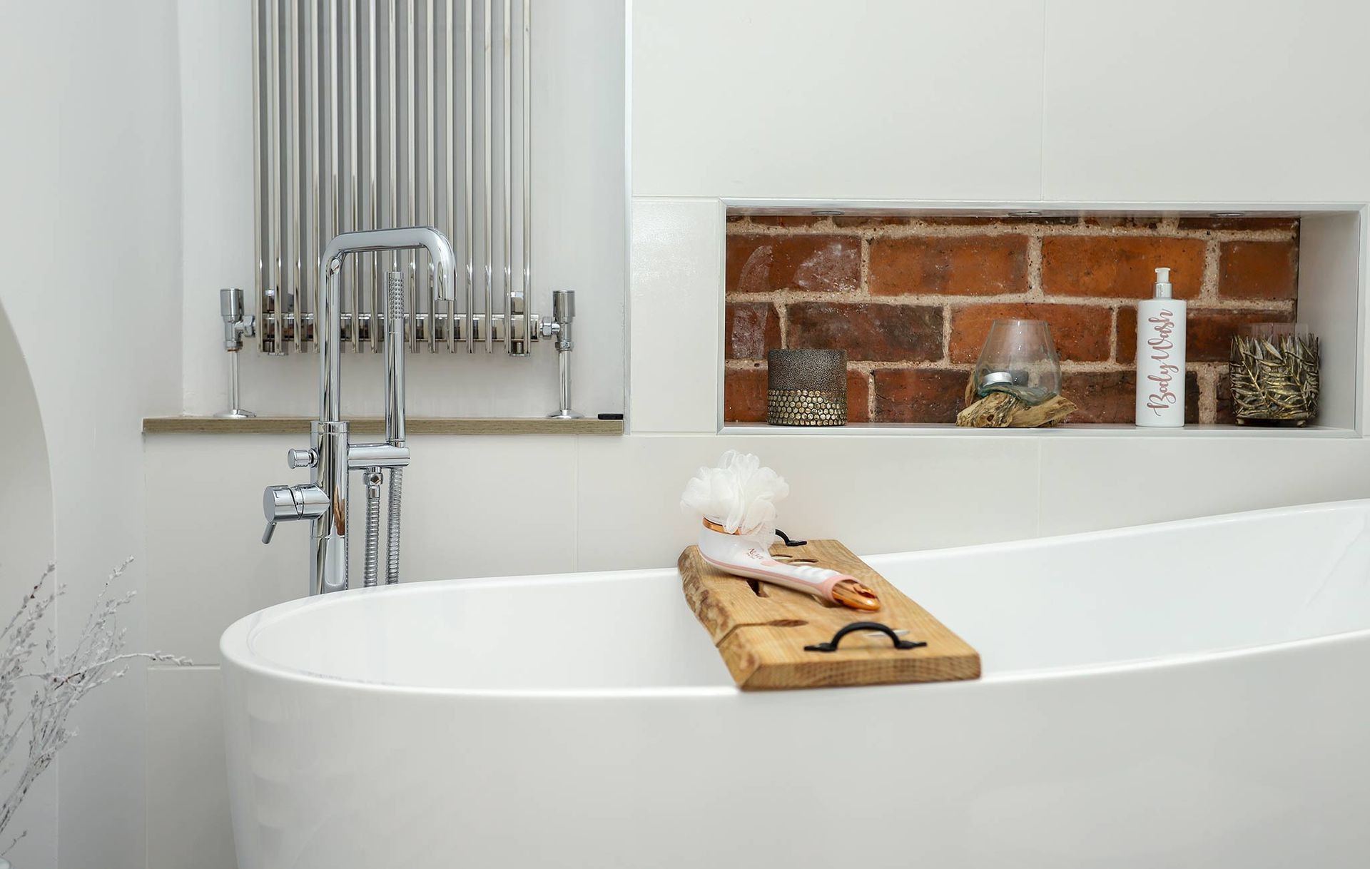 A bathtub in a bathroom with a brick wall behind it