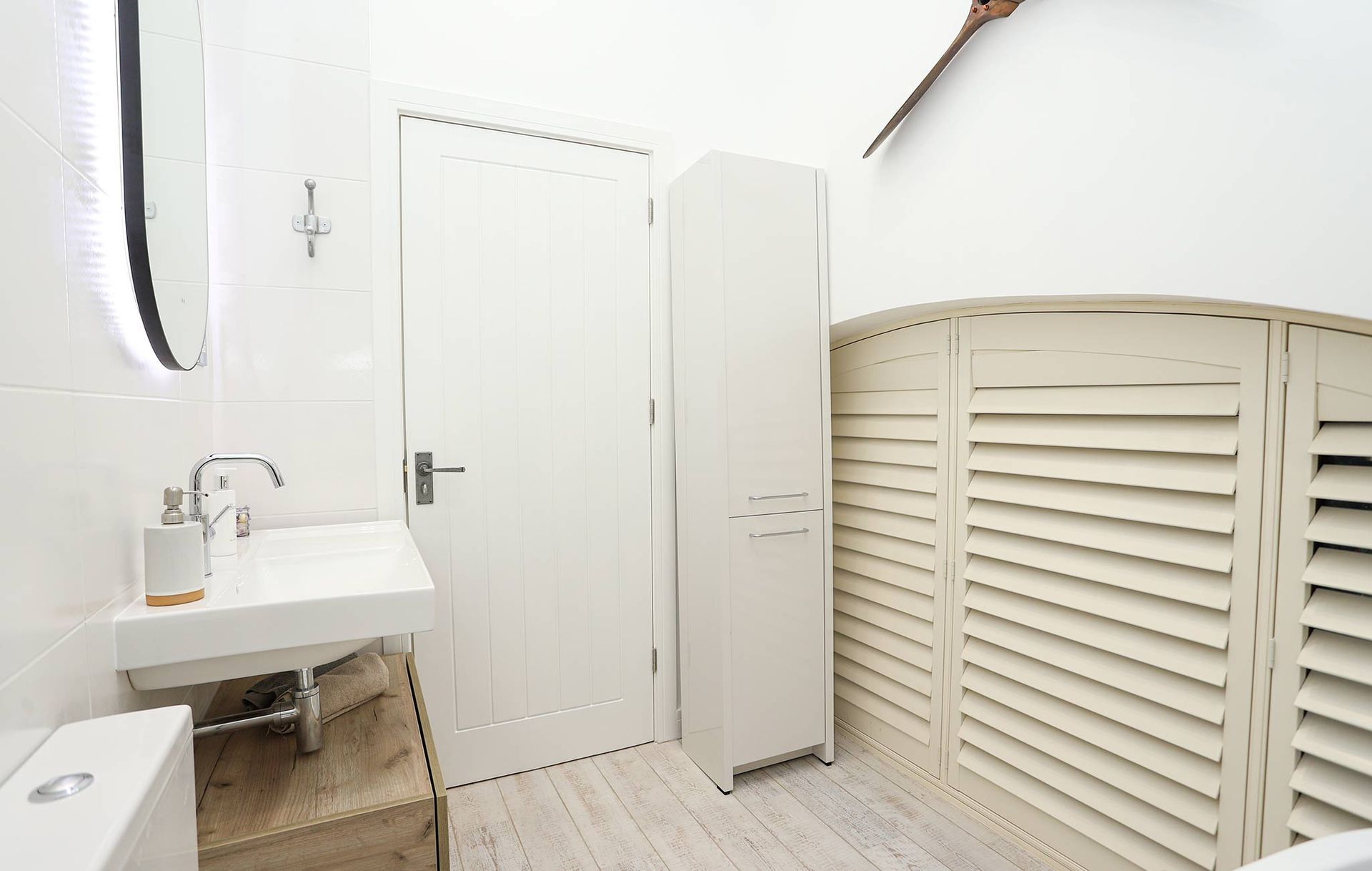 A bathroom with white shutters and a sink