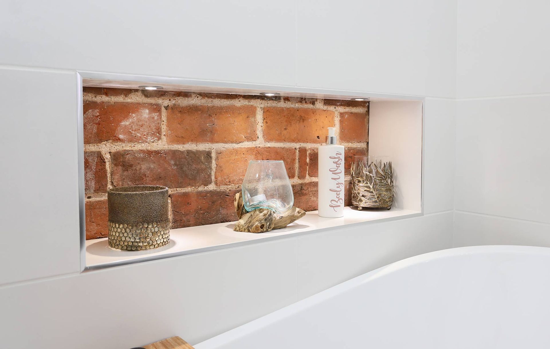 A bathroom with a brick wall and a bathtub with a shelf in the wall