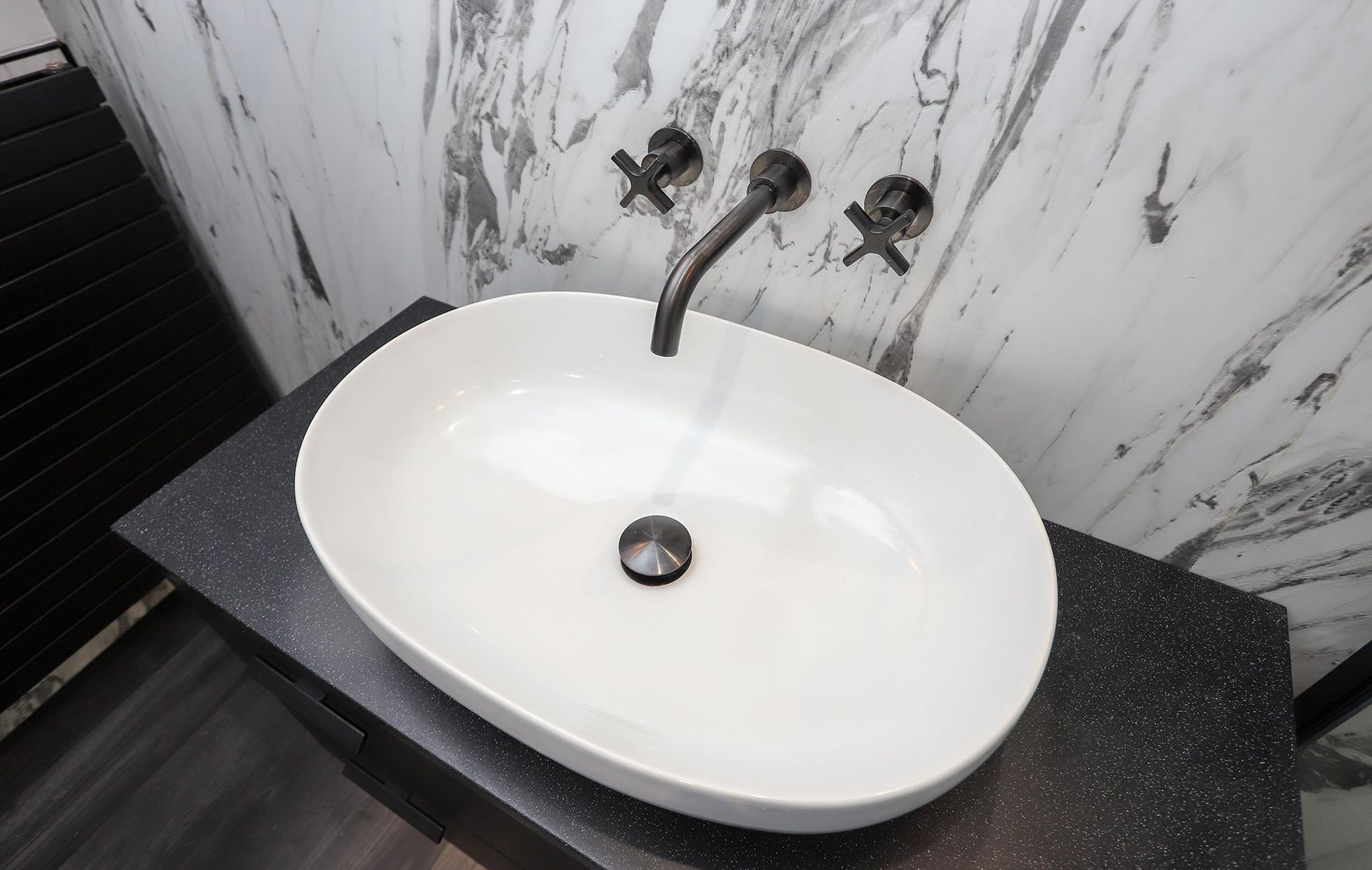 A white sink is sitting on a black counter in a bathroom.