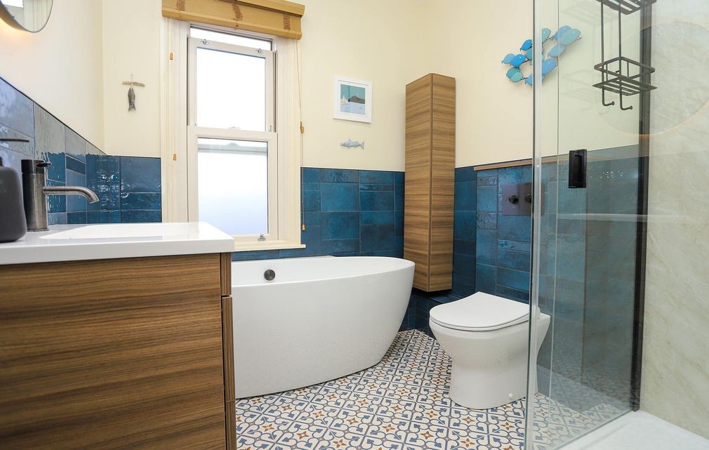 A bathroom with blue tiles and a white tub